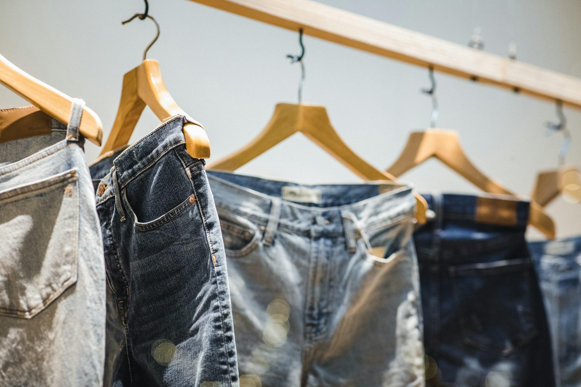 Mehrere Jeans an Kleiderbügeln.