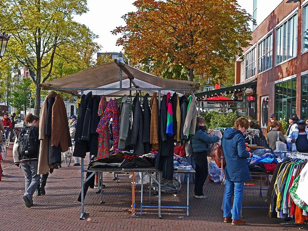 Ein Flohmarkt draußen mit vielen Kleidungsstücken.