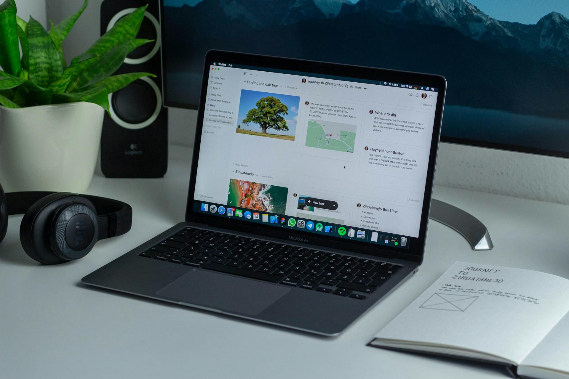Aufgeklappter Laptop auf Tisch neben Heft und Kopfhörern.