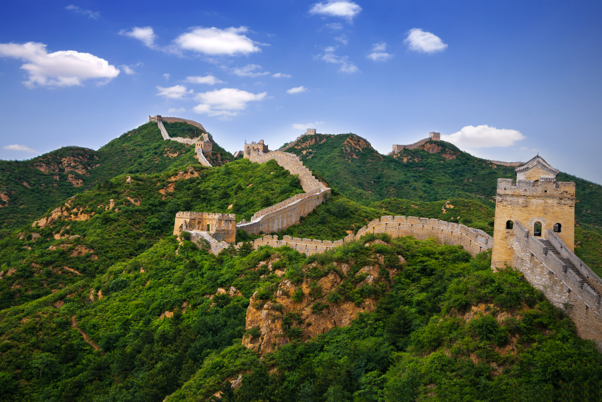 Die chinesische Mauer zieht sich durch eine grüne Berglandschaft