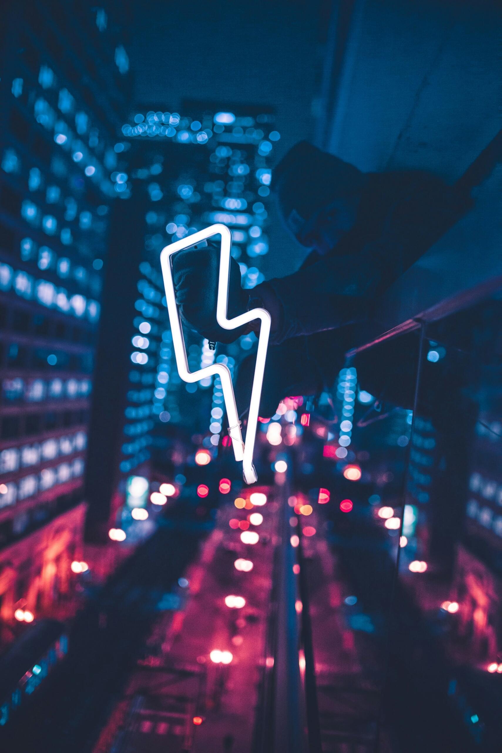 Ein neon-leuchtender Blitz vor einer im dunklen erleuchteten Skyline.