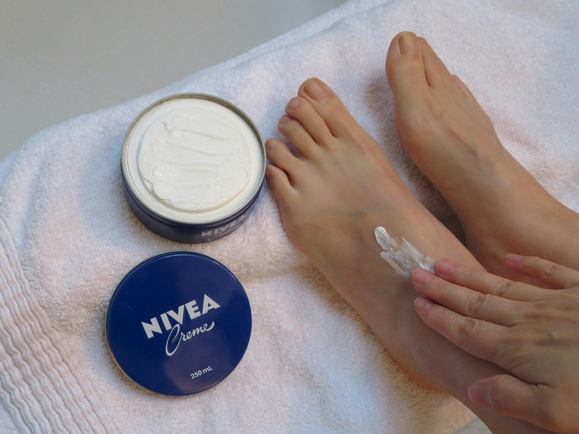 Eine Frau cremt ihre Füße mit Nivea ein.