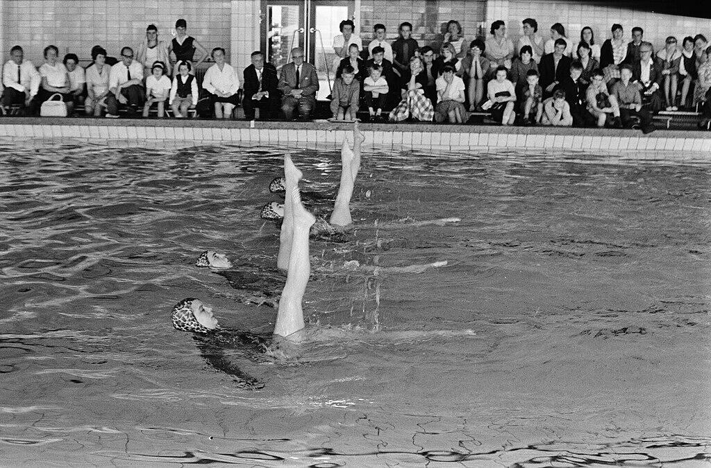 Vier Synchronschwimmerinnen heben ein Bein in die Luft.