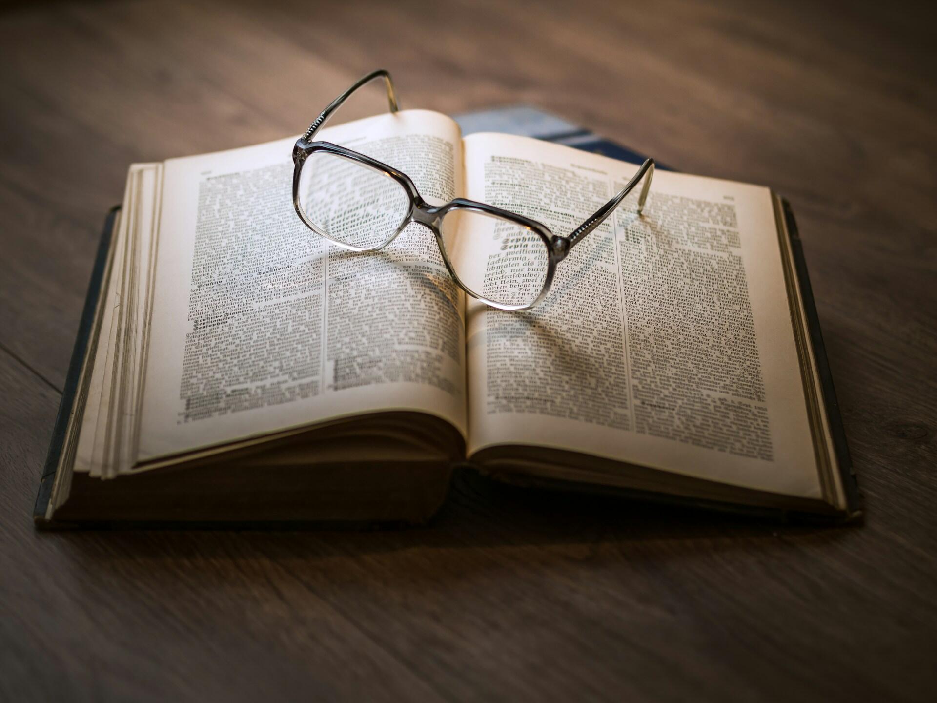 Aufgeschlagenes Buch mit Brille darauf