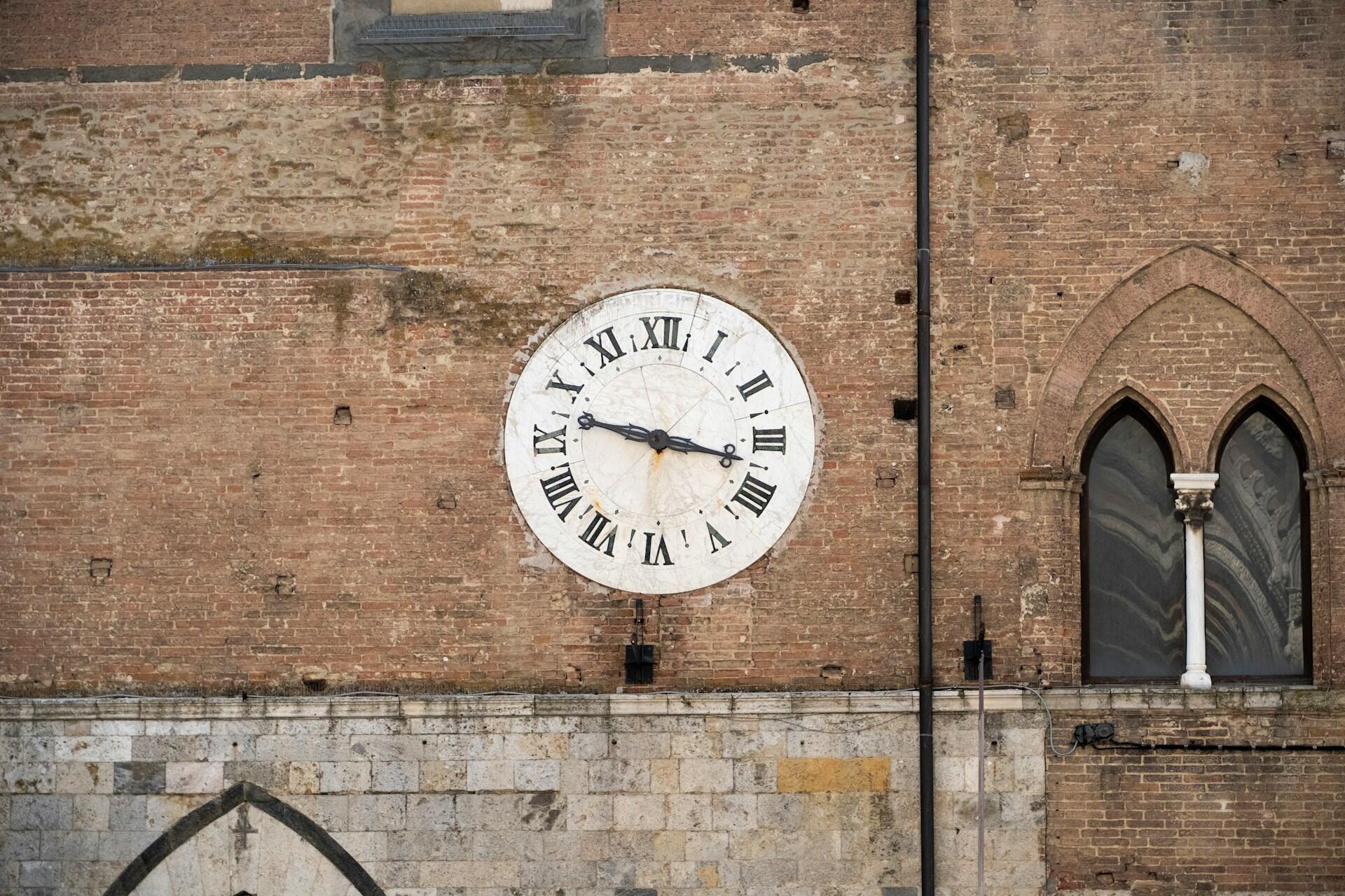 Eine große Uhr an einer Gebäudewand mit römischen ziffern.