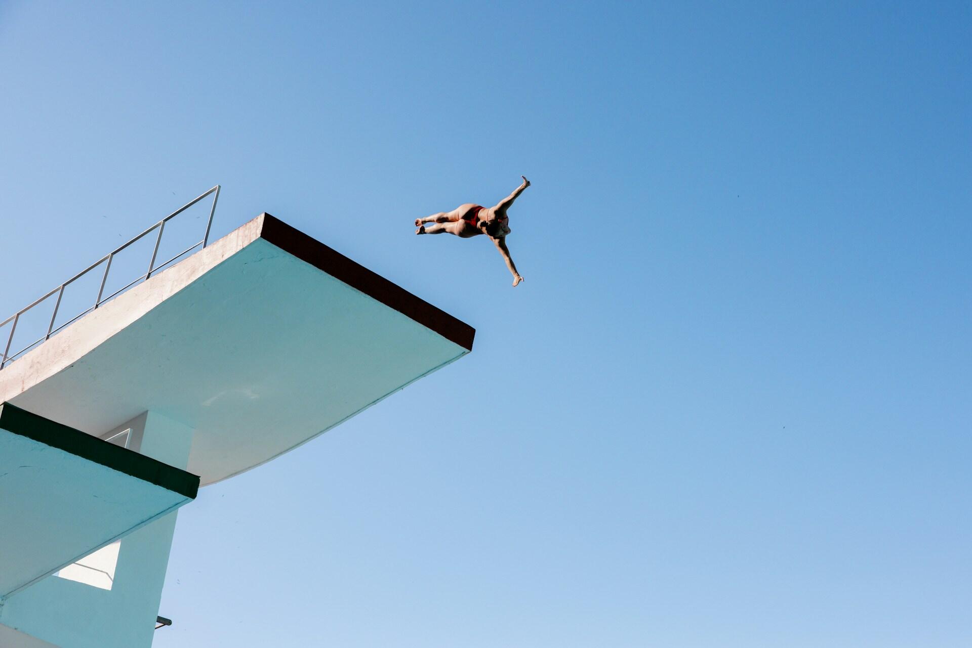 Person springt kopfüber von einem Sprungturm