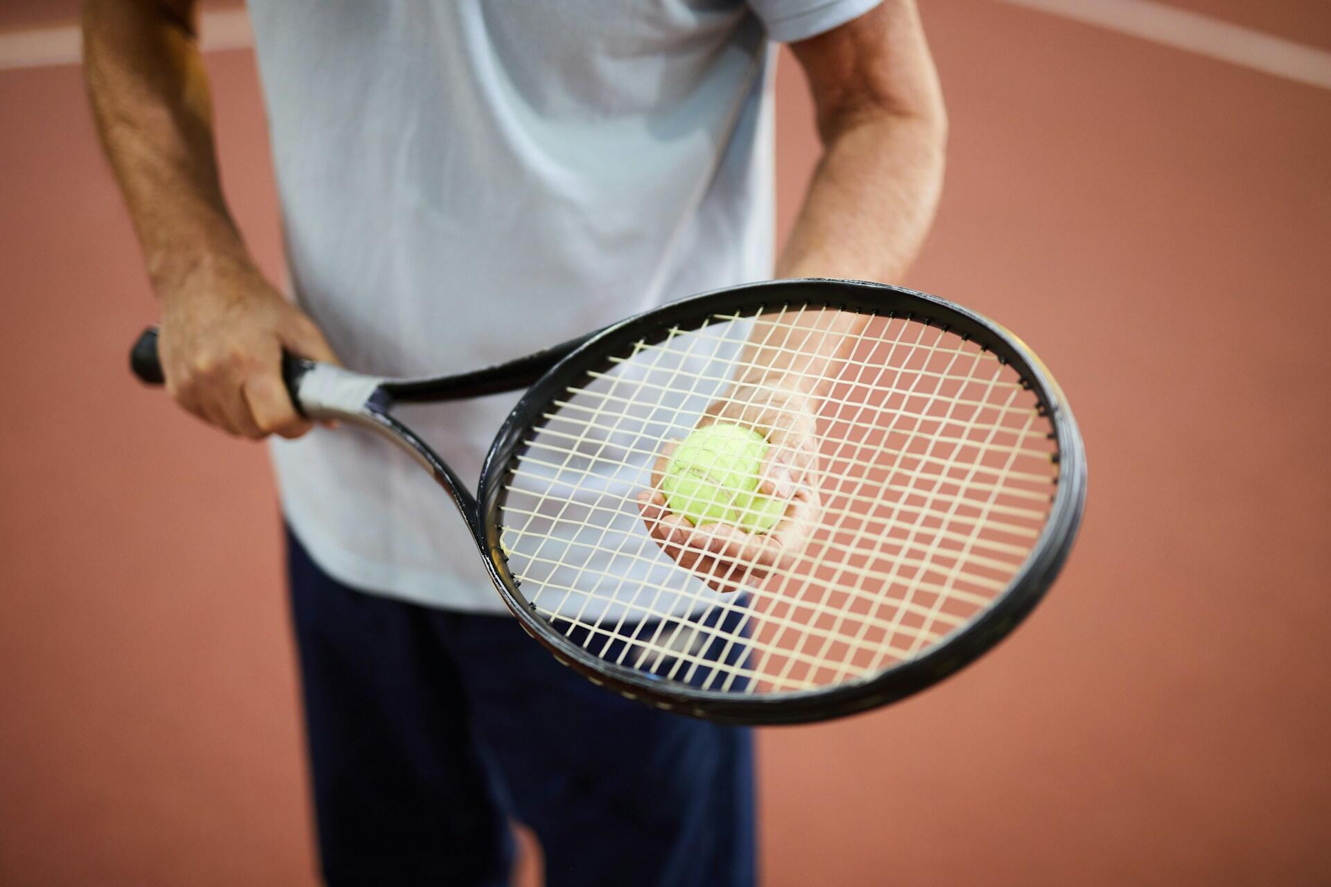 Person auf einem Tennisplatz mit Schläger und Ball