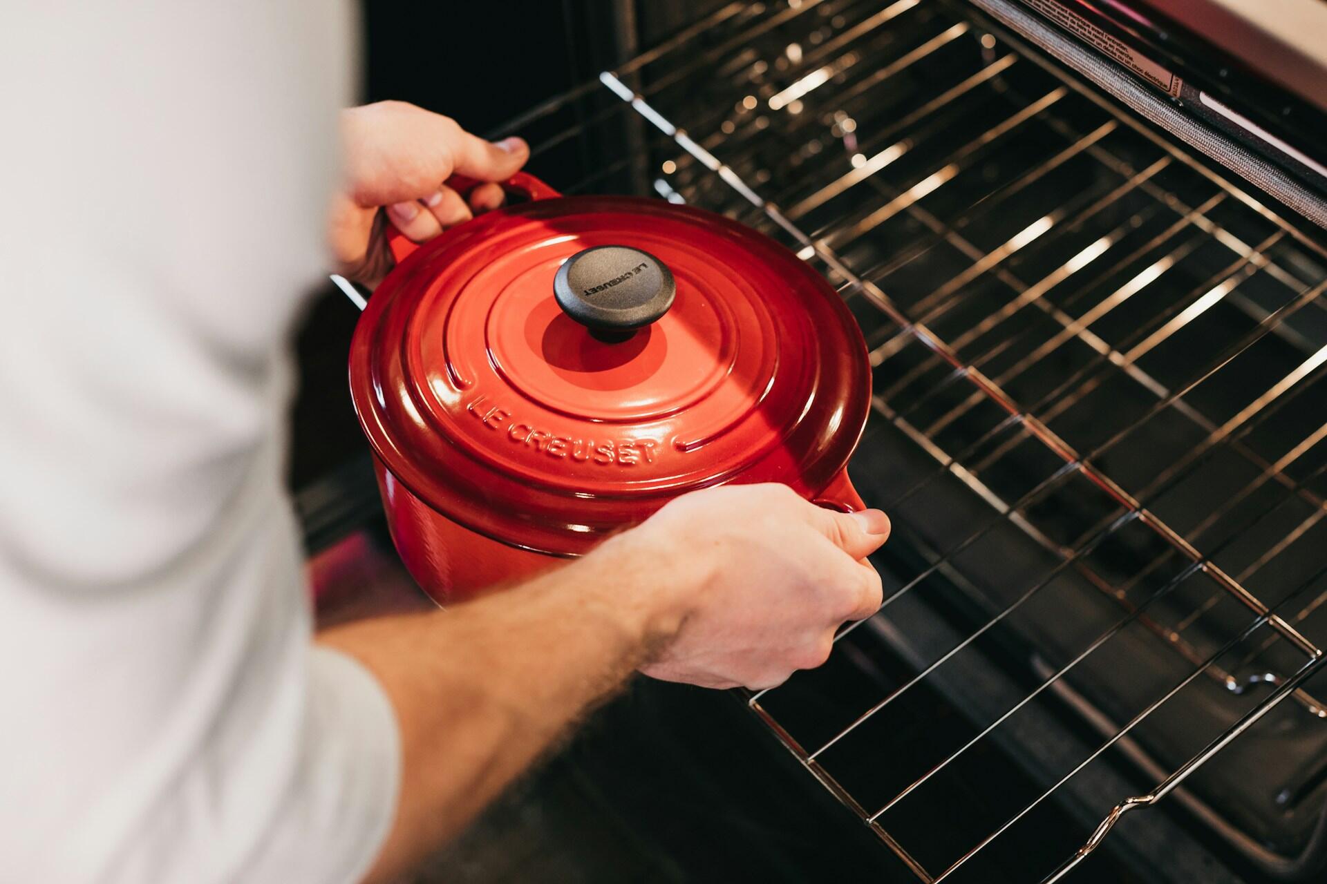 Person stellt einen Topf zum Einkochen in den Backofen