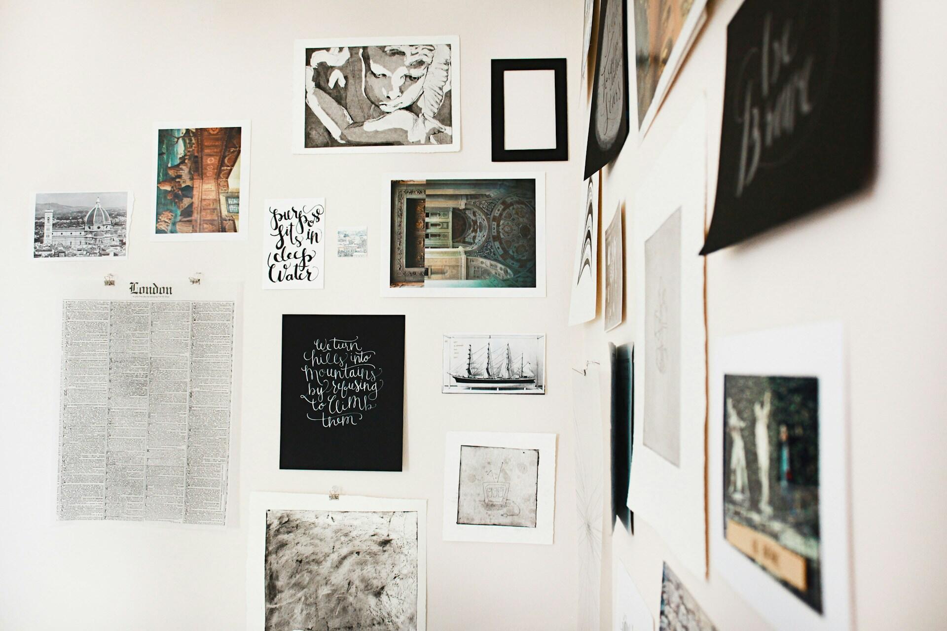 Viele kleine Bilder und Prints hängen an einer weißen Wand über Eck.