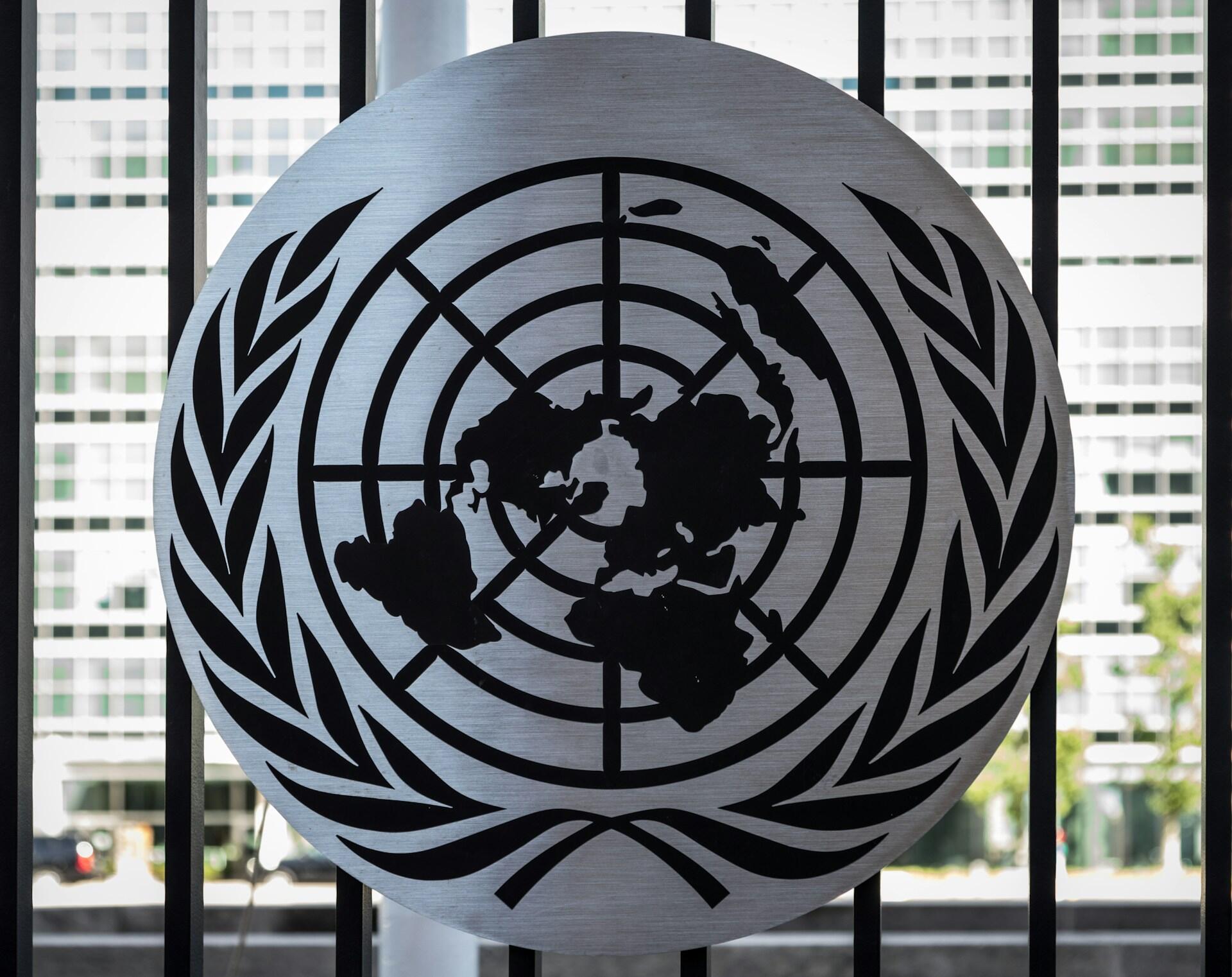 Das Emblem der Vereinten Nationen vor einem Fenster