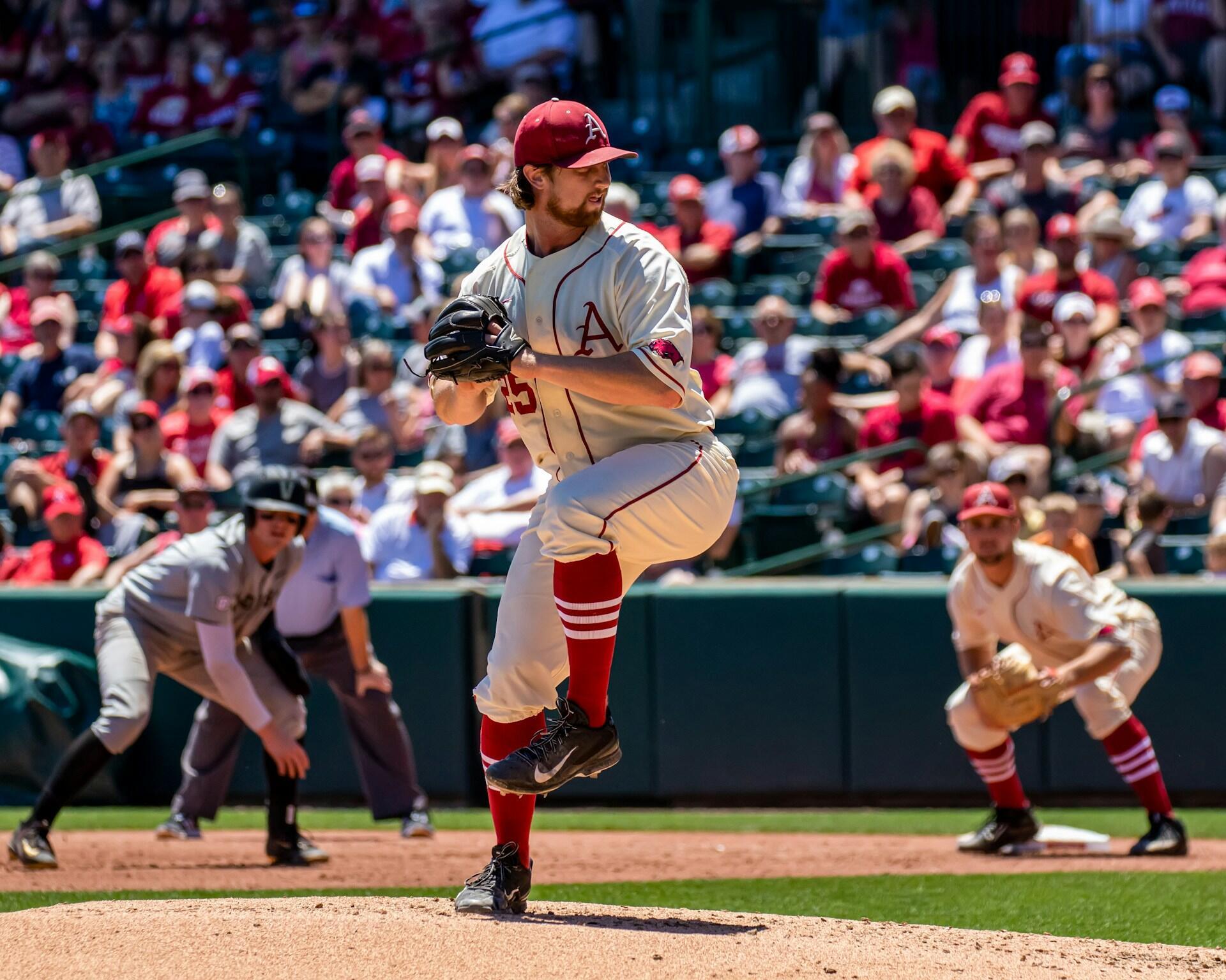 Ein Baseballspieler auf dem Spielfeld, bereit, den Ball zu werfen, vor einer Tribüne voller Zuschauer.