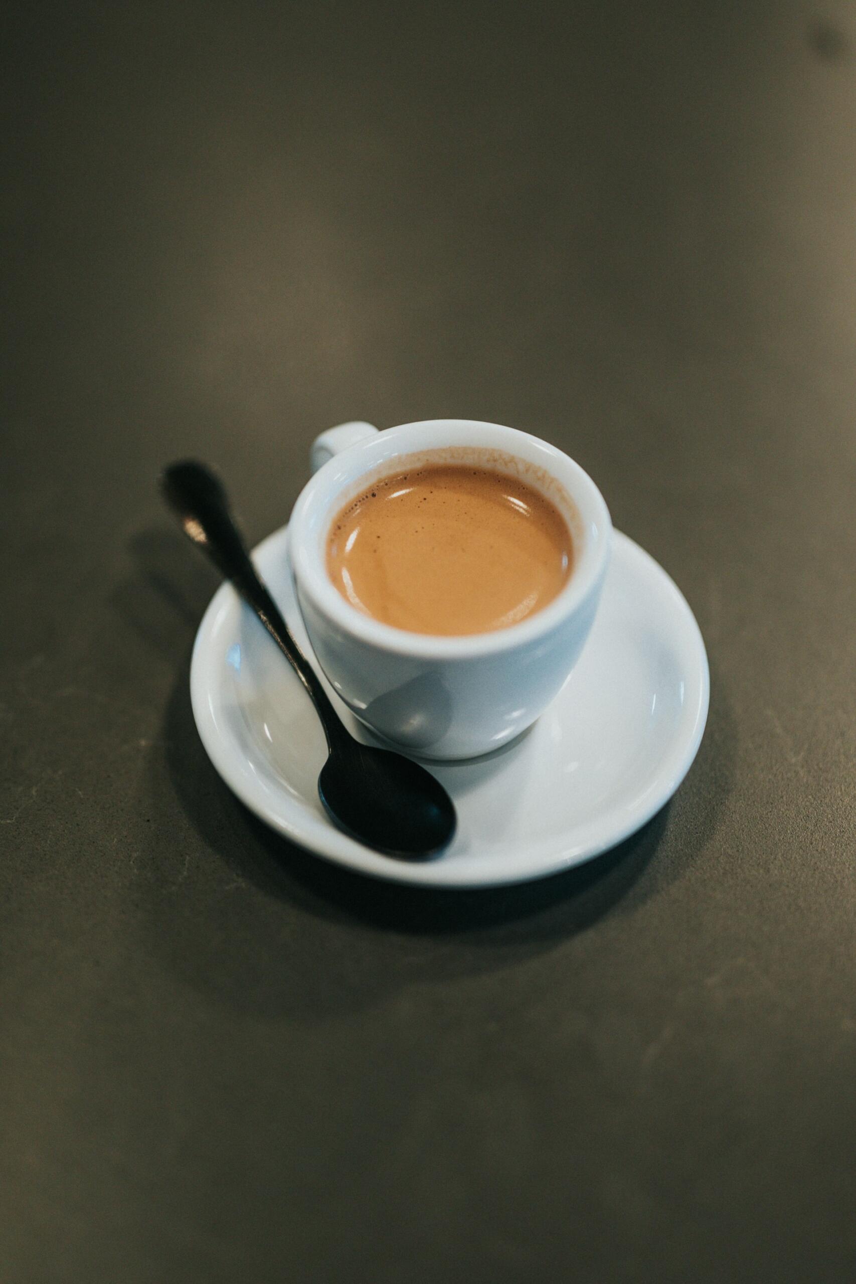 Volle Espresso-Tasse auf einem Unterteller mit einem Löffel