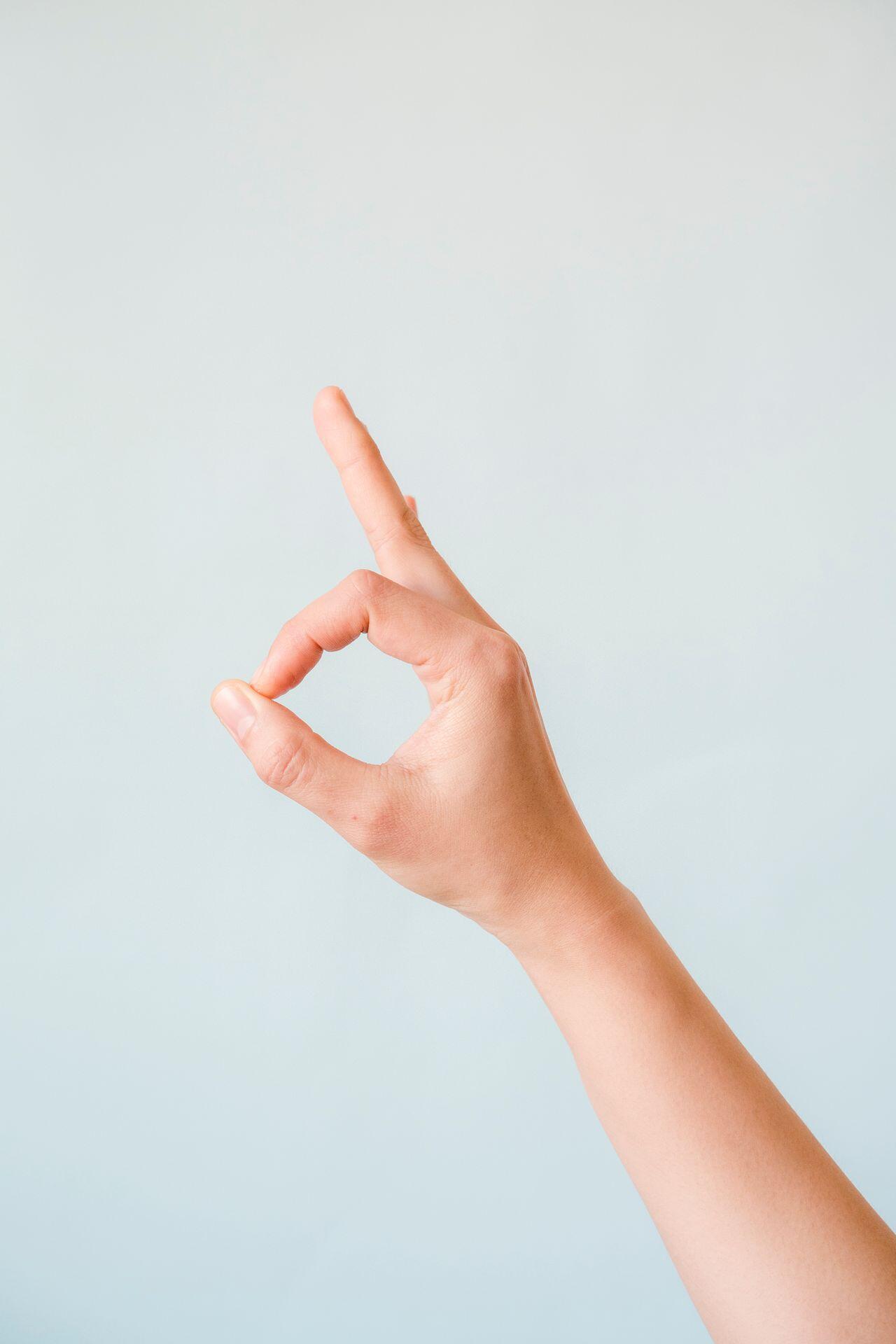 Eine hochgestreckte Hand, bei der Daumen und Zeigefinger ein O formen.