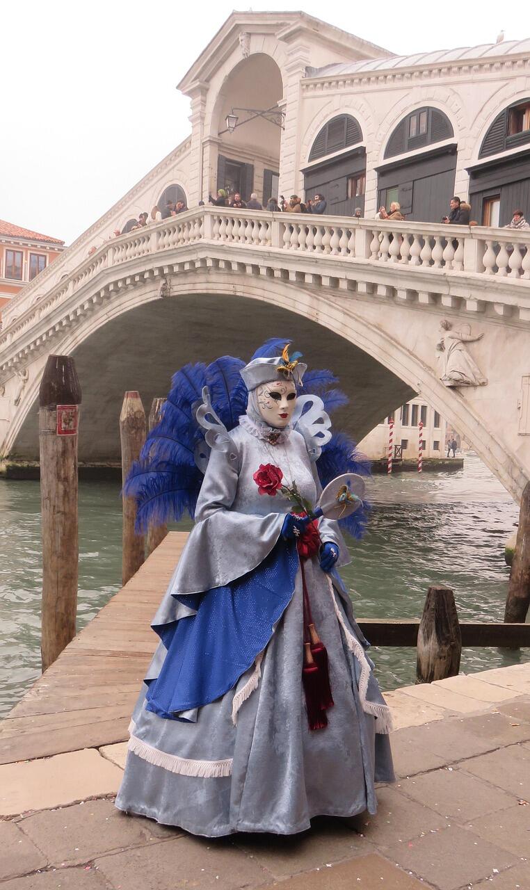 Karnelvalsfigur mit Maske vor einer Brücke