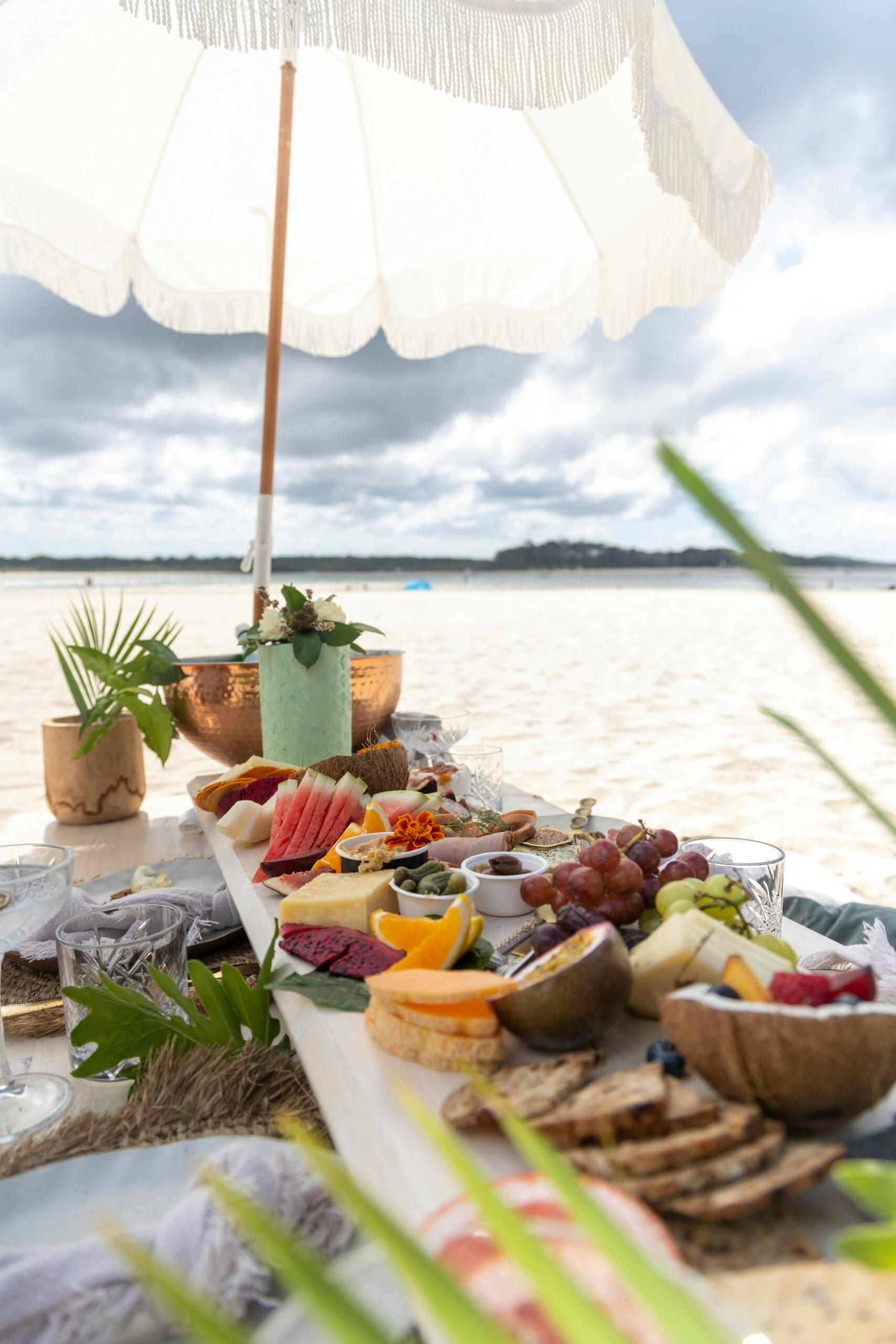Brot, Obst und Oliven auf einem Holztisch am Strand