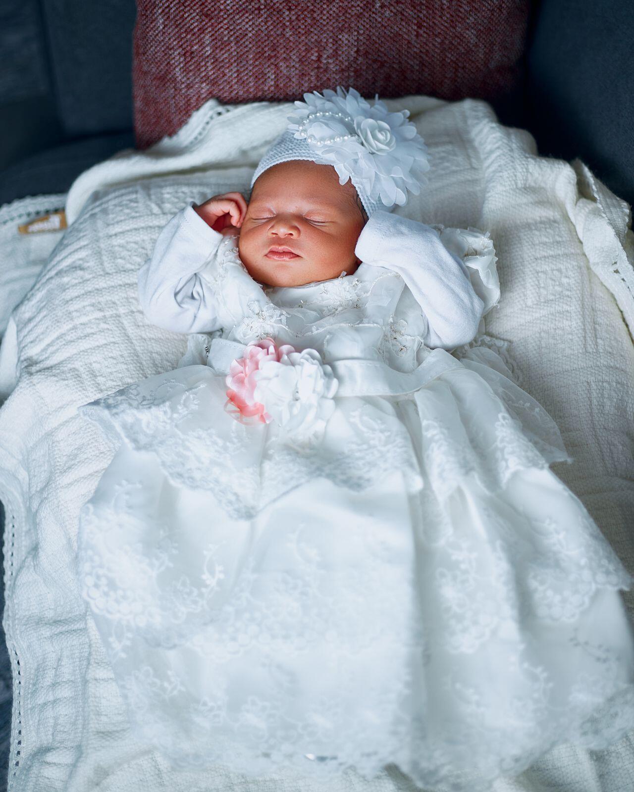 Baby im weißen Taufkleid in weiße Tücher gebettet