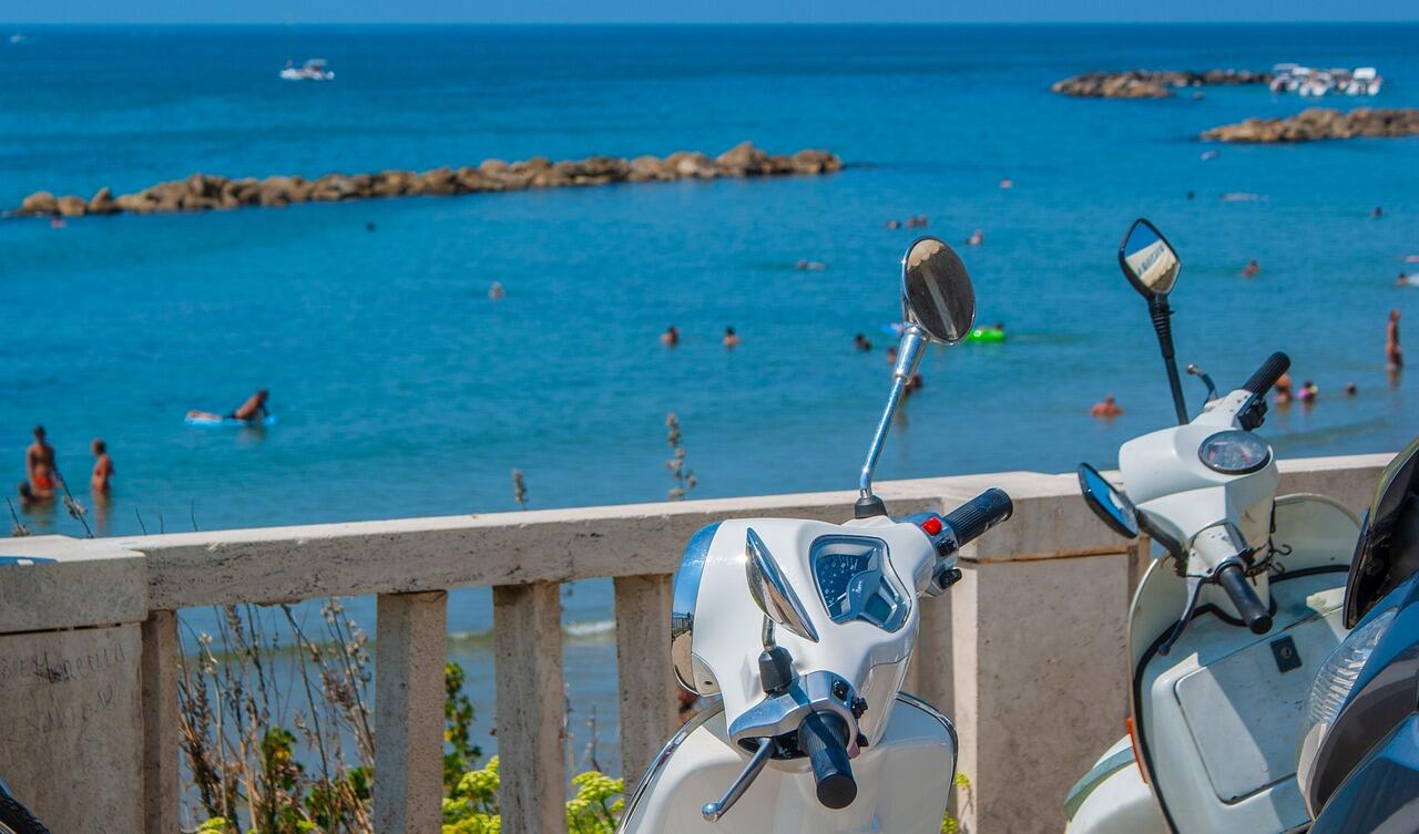 Zwei Vespas vor einem Strand