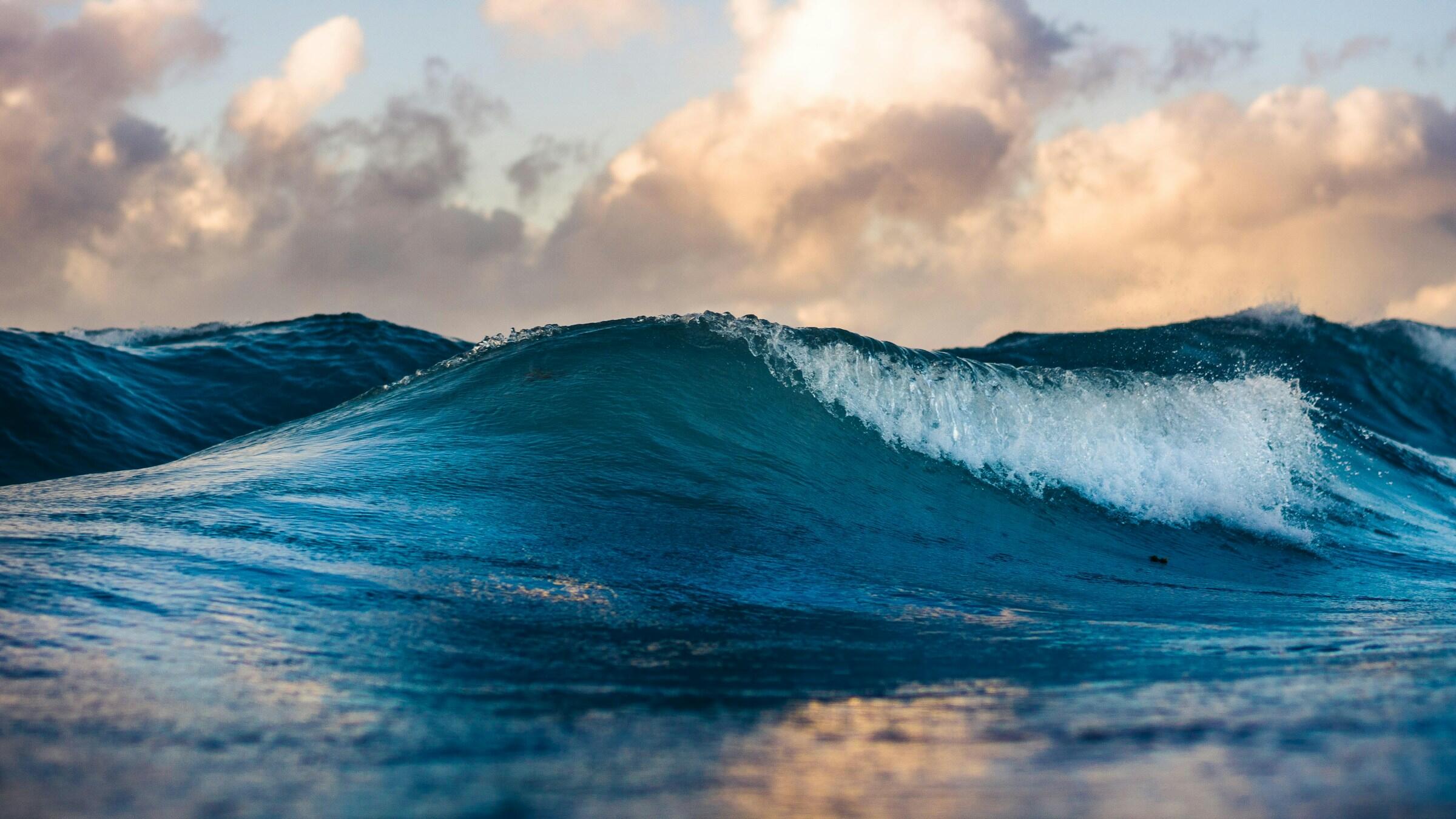 Eine Welle auf dem Wasser und im Hintergrund Himmel und Wolken.