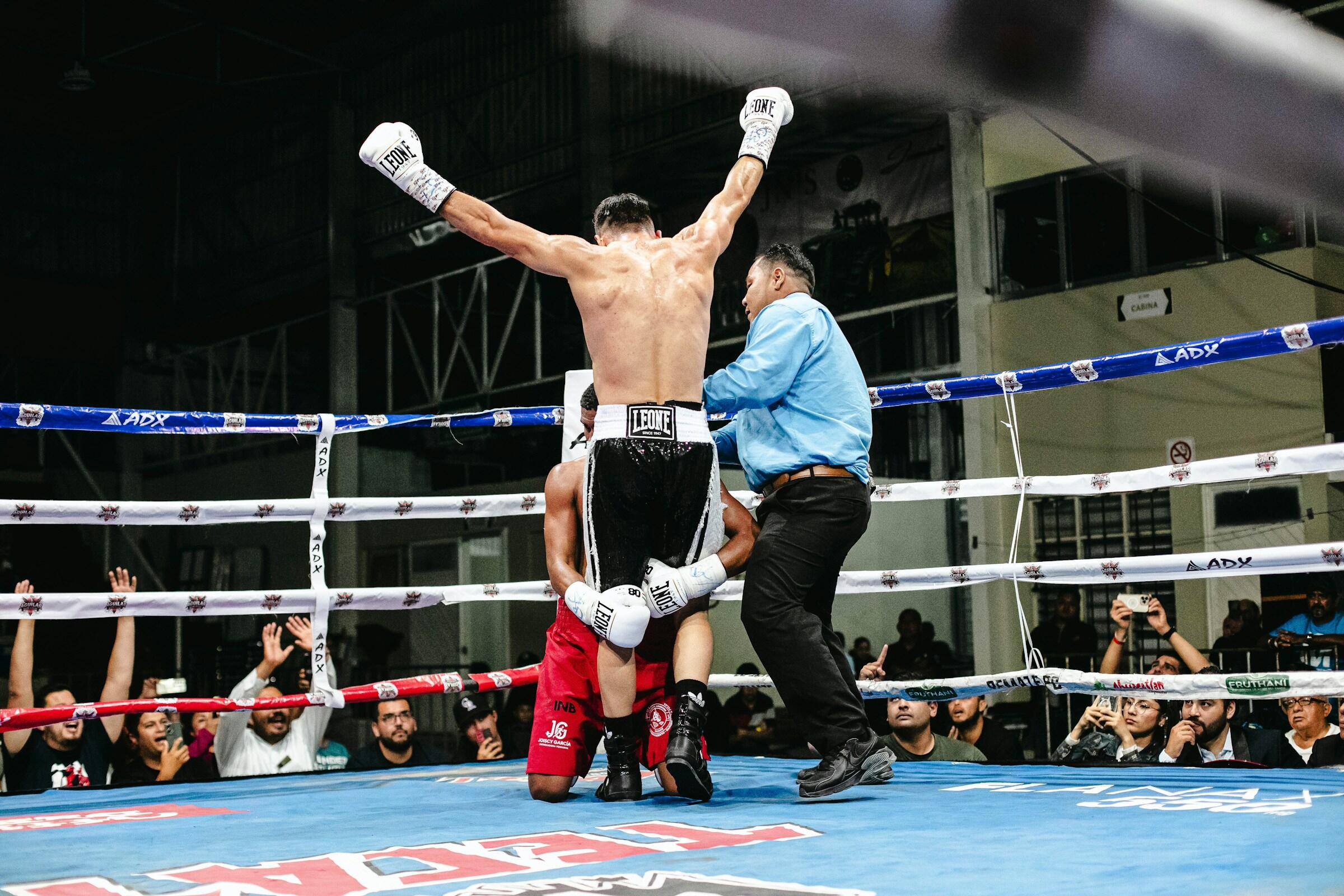 EIn Boxer klammert dem anderen die Beine und der Ringrichter geht dazwischen.