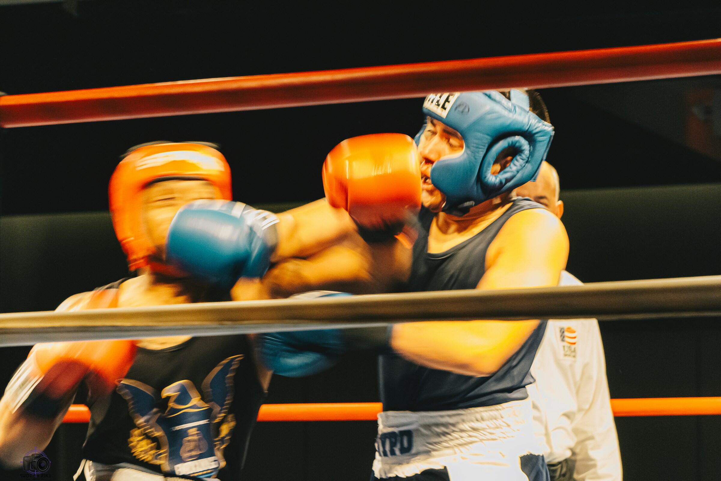 Zwei Boxer boxen sich mit Kopfschutz und Handschuhen.