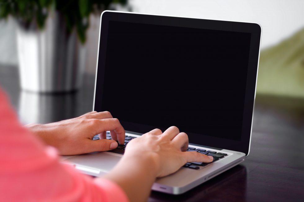 Hænder på en computer med sort skærm