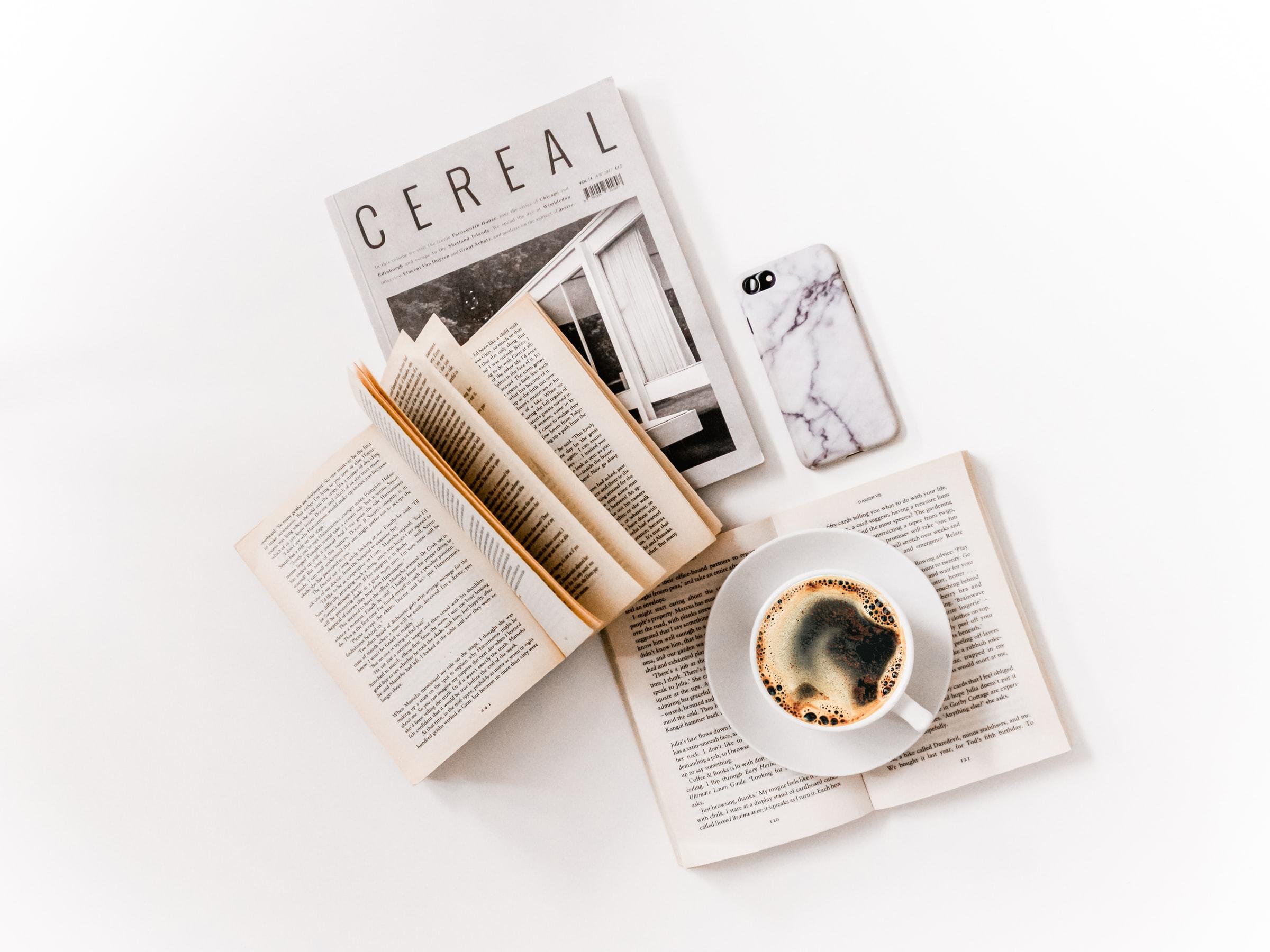 litteratur på hvidt skrivebord med en kop kaffe på