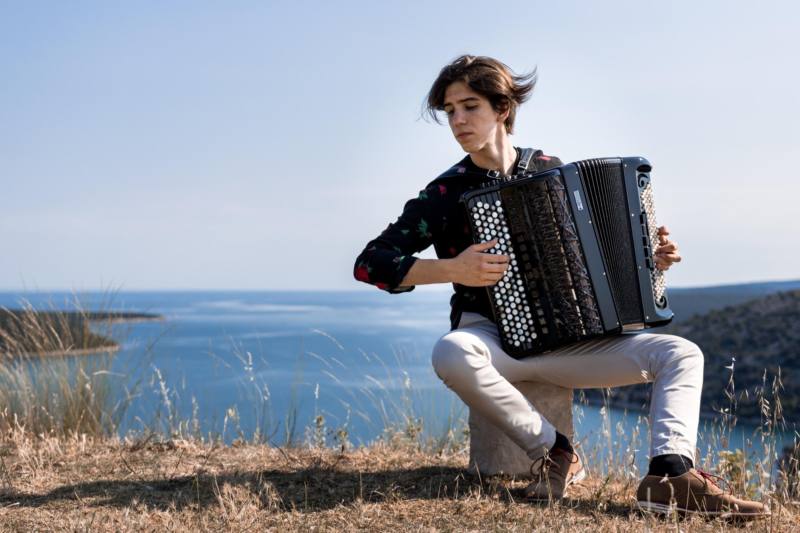 Mand spiller harmonika udenfor og spiller franske sange som er gode til når man vil lære at spille guitar