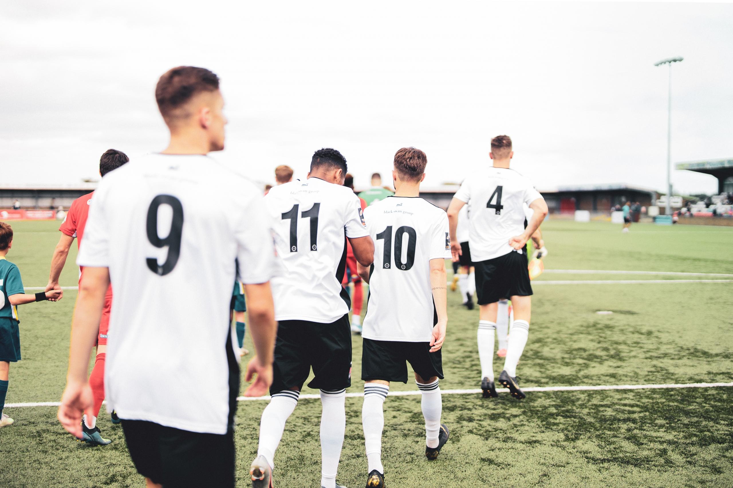 Fire fodboldspillere på vej mod banen, hvor de vil spille med en defensiv fodbold taktik
