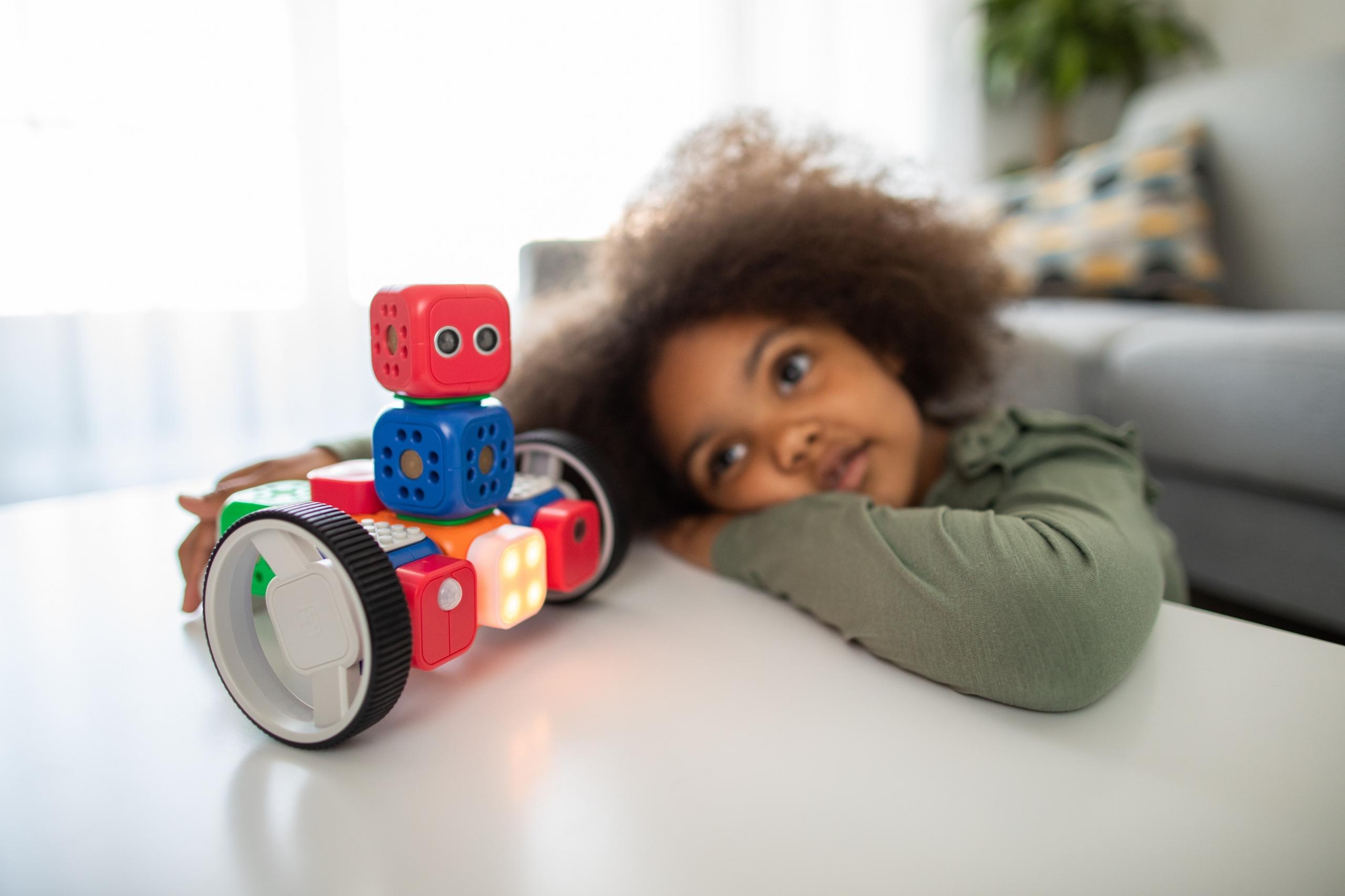 En pige sidder ved et bord med en robot, fordi hun har lært matematik for børn