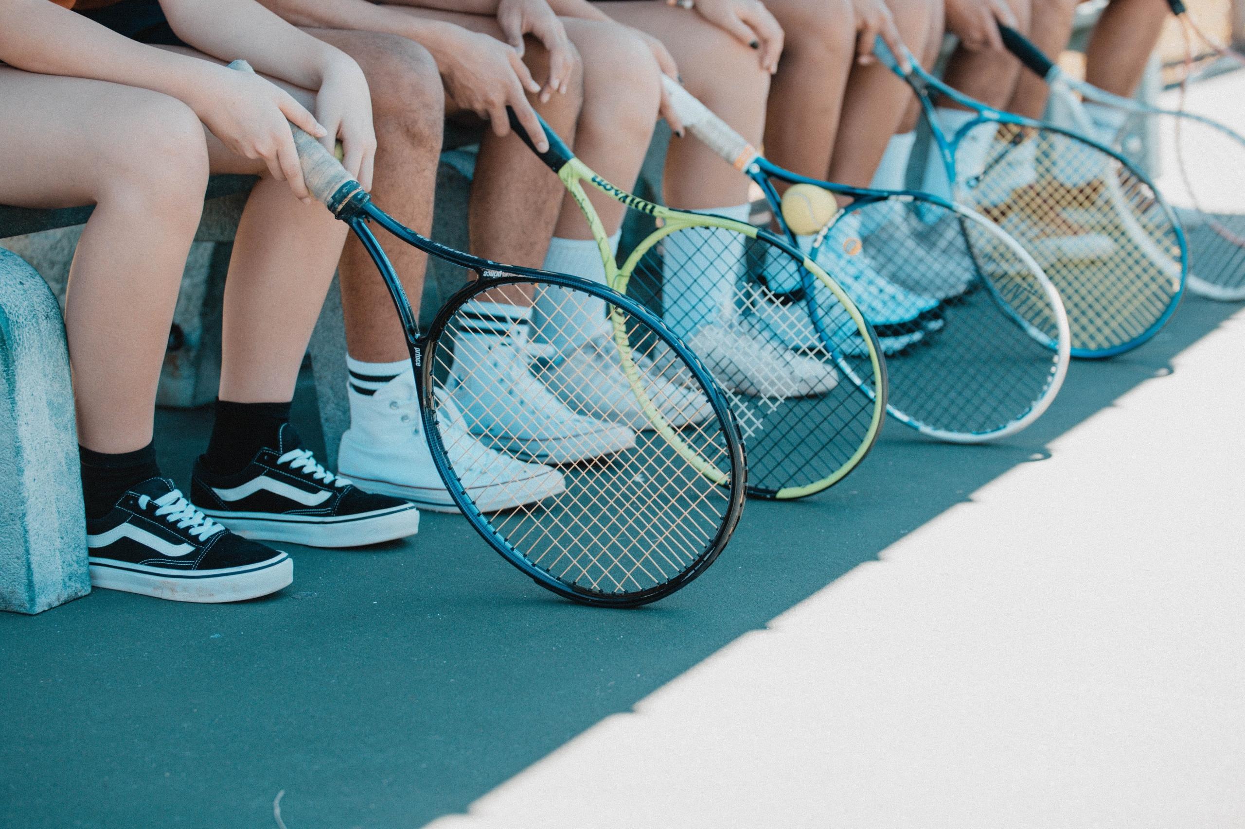 En række tennisspillere sidder klar med deres tennisketcher