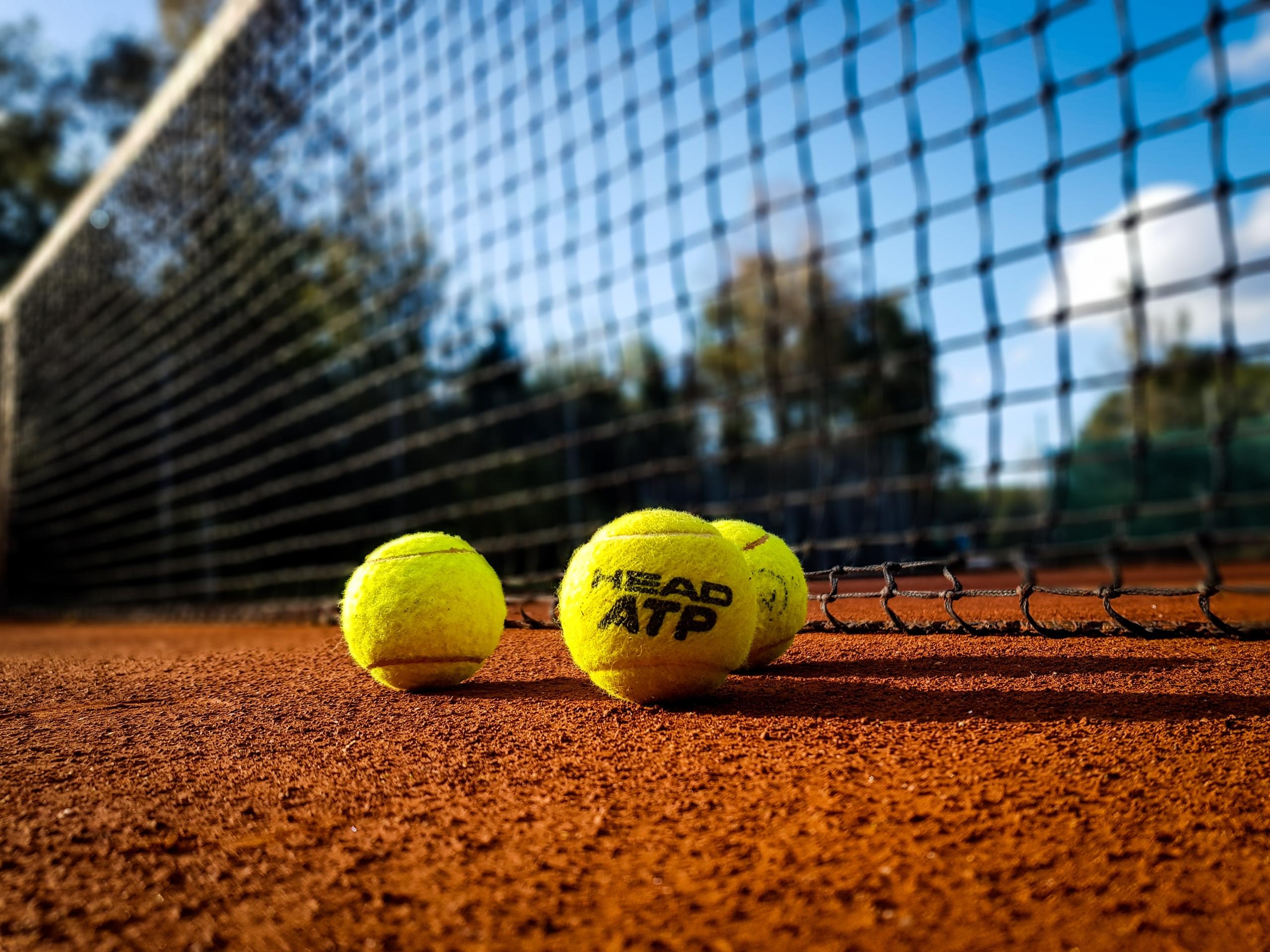 Gule tennisbolde på en bane lagt klar af en tennis coach