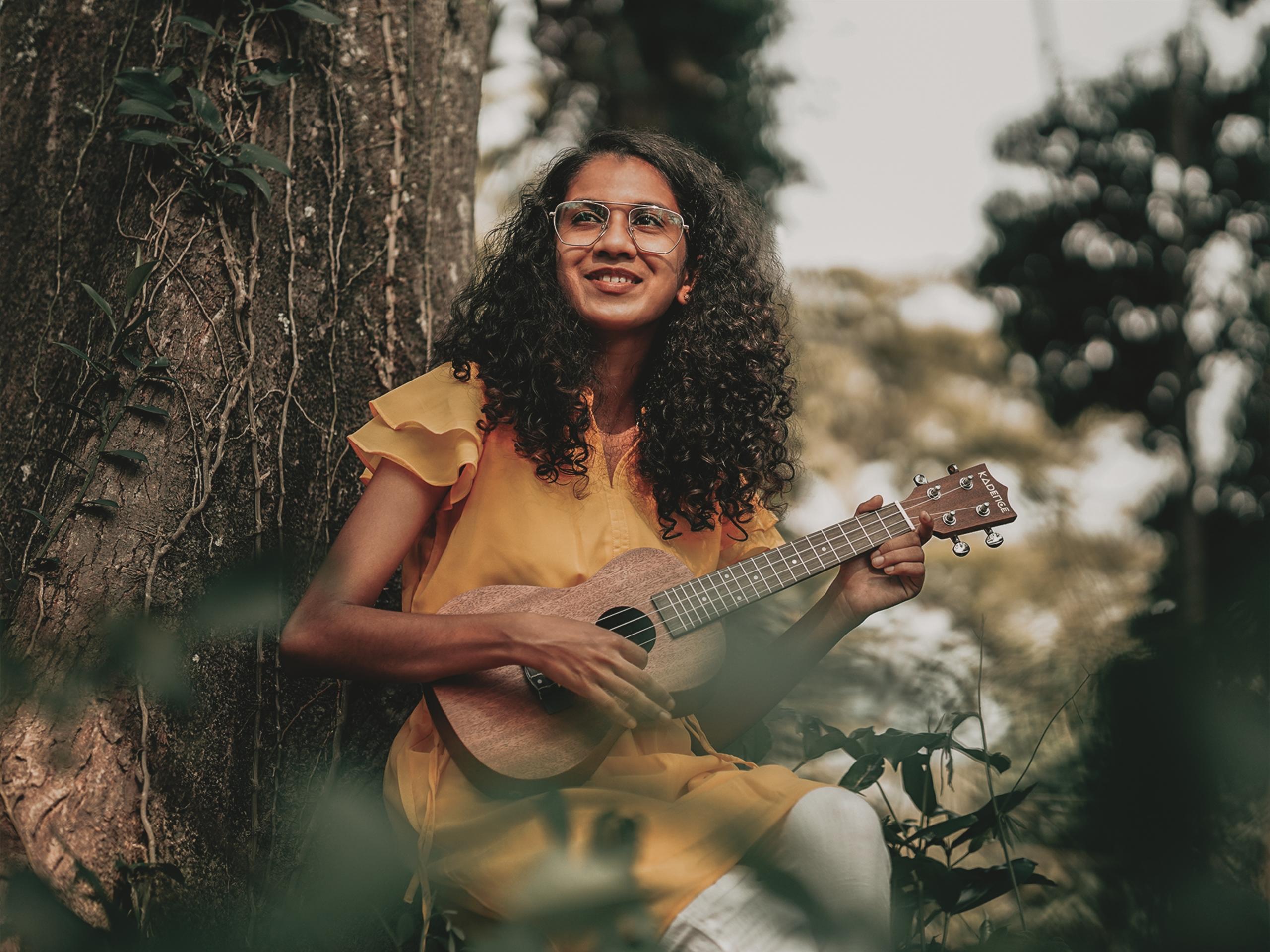 en pige spiller ukulele udenfor