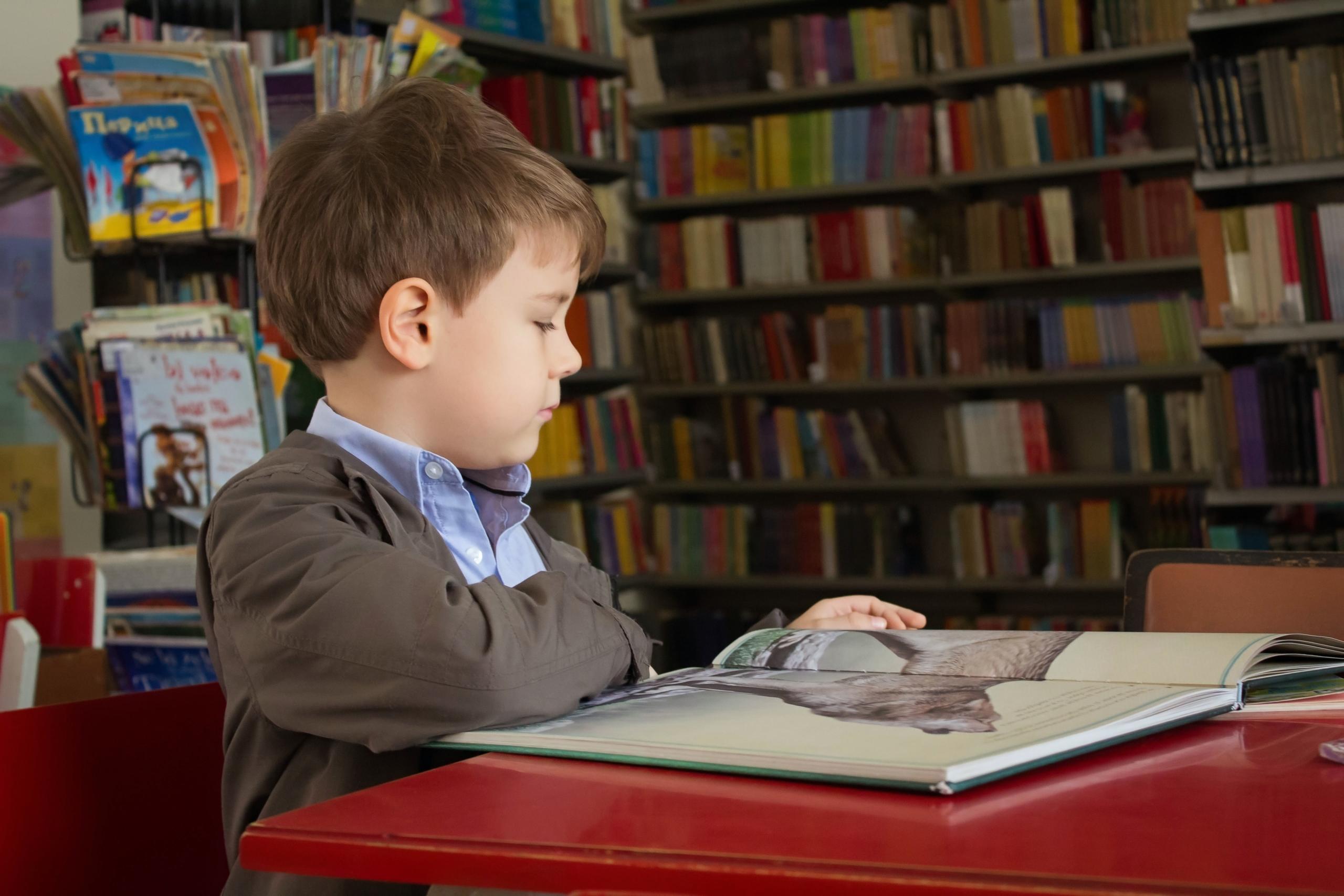 En dreng træner børns læsefærdigheder på et bibliotek