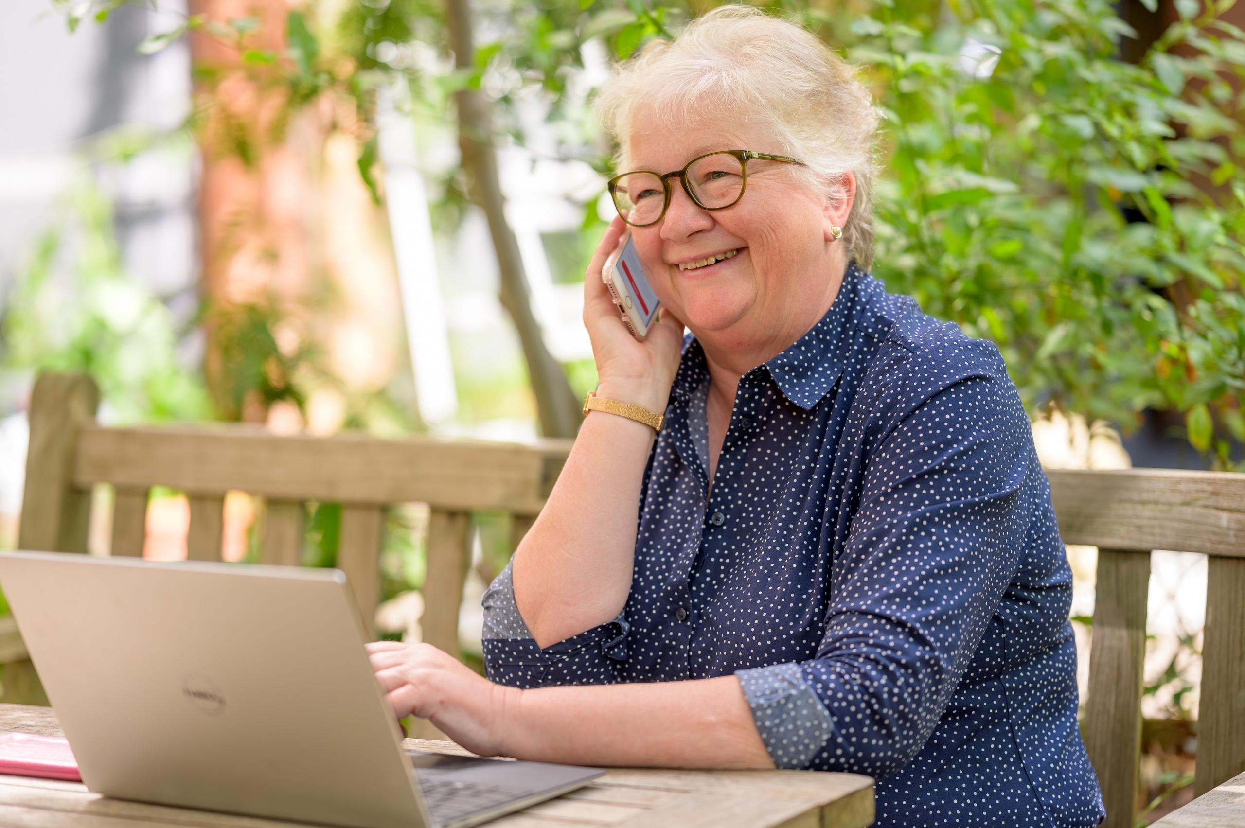 Kvinde snakker i telefon foran computeren