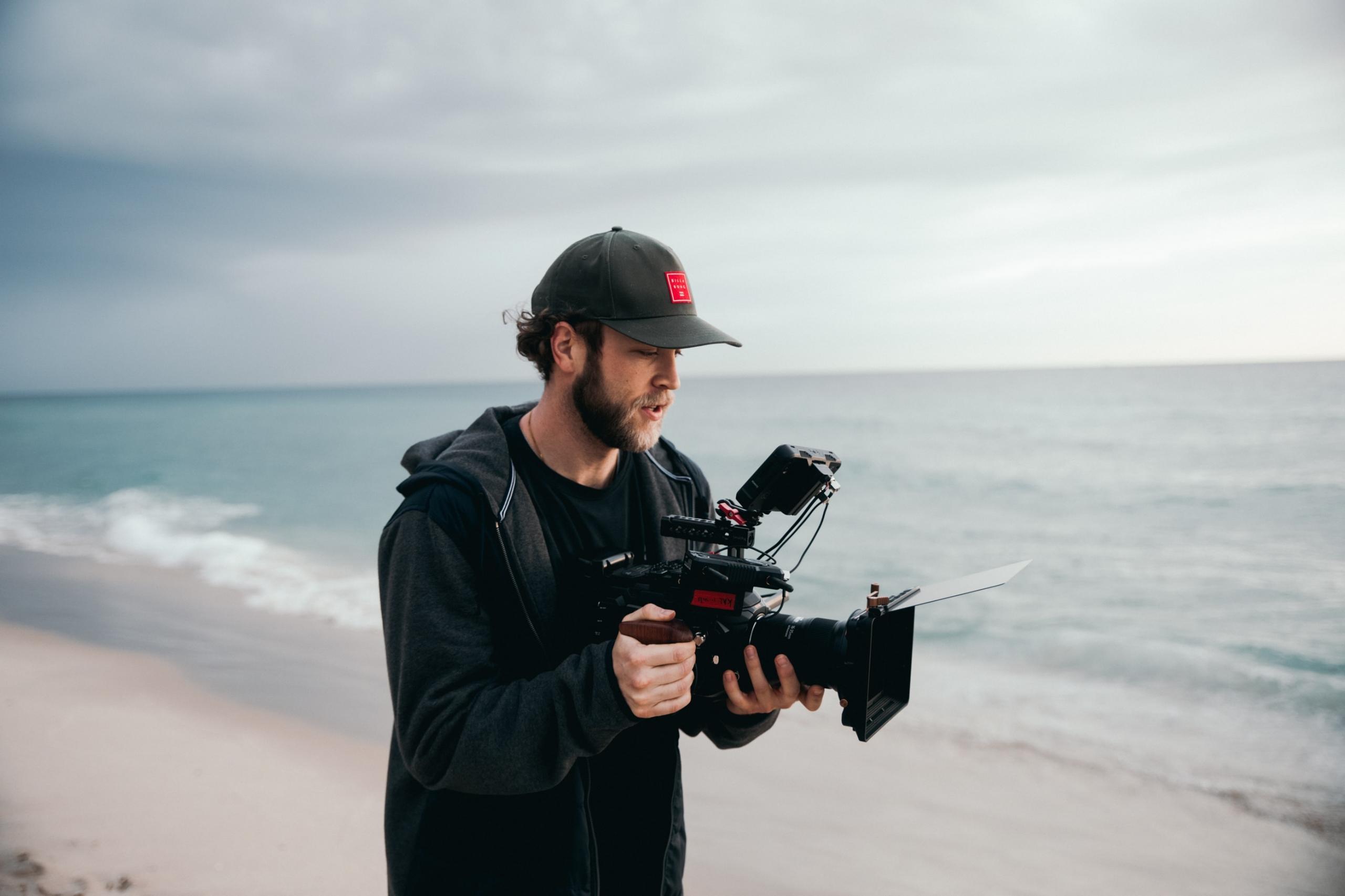 En videograf på en strand med et kamera