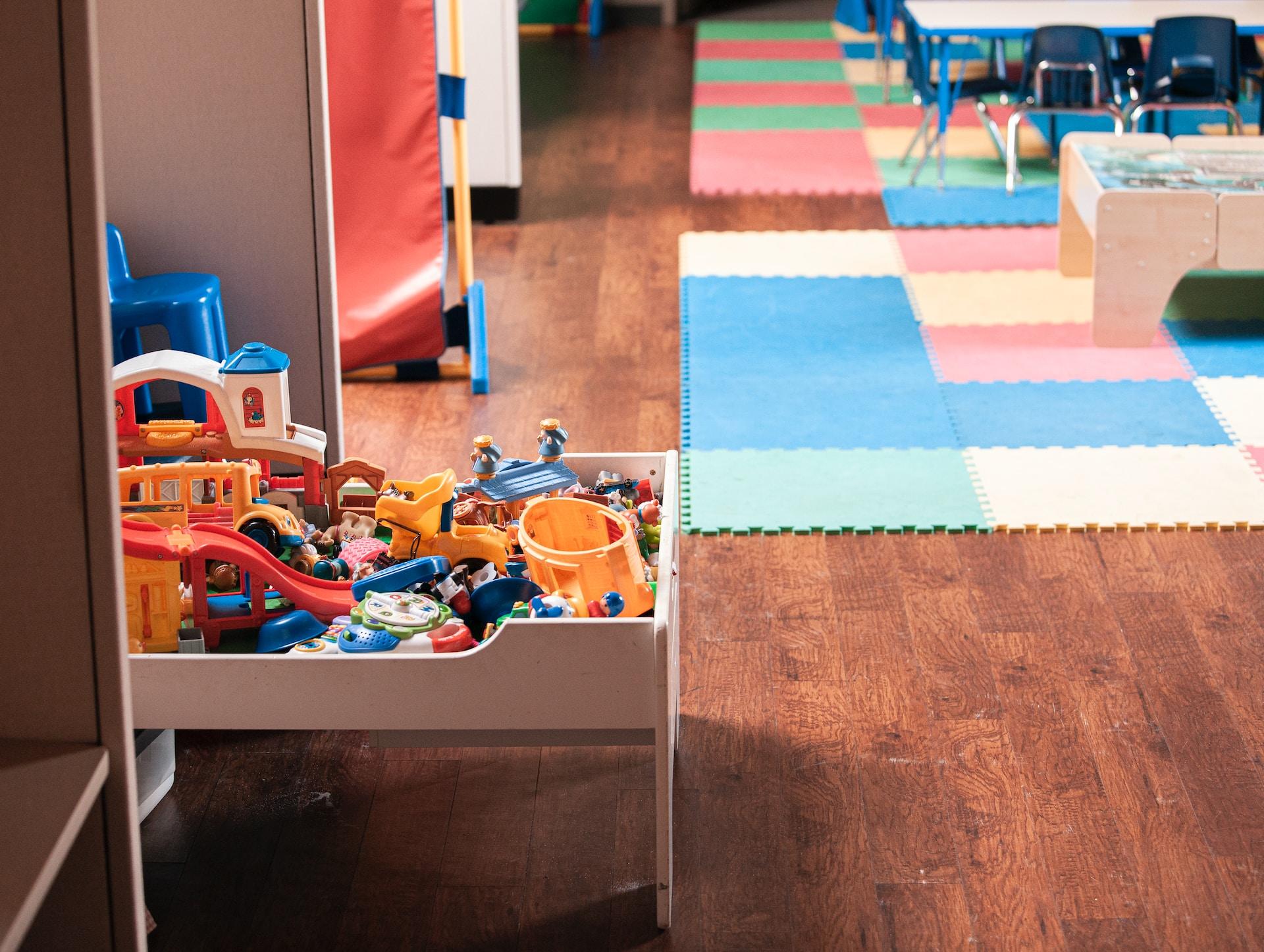 Raum mit Spielmatten und Kiste mit Spielzeug.