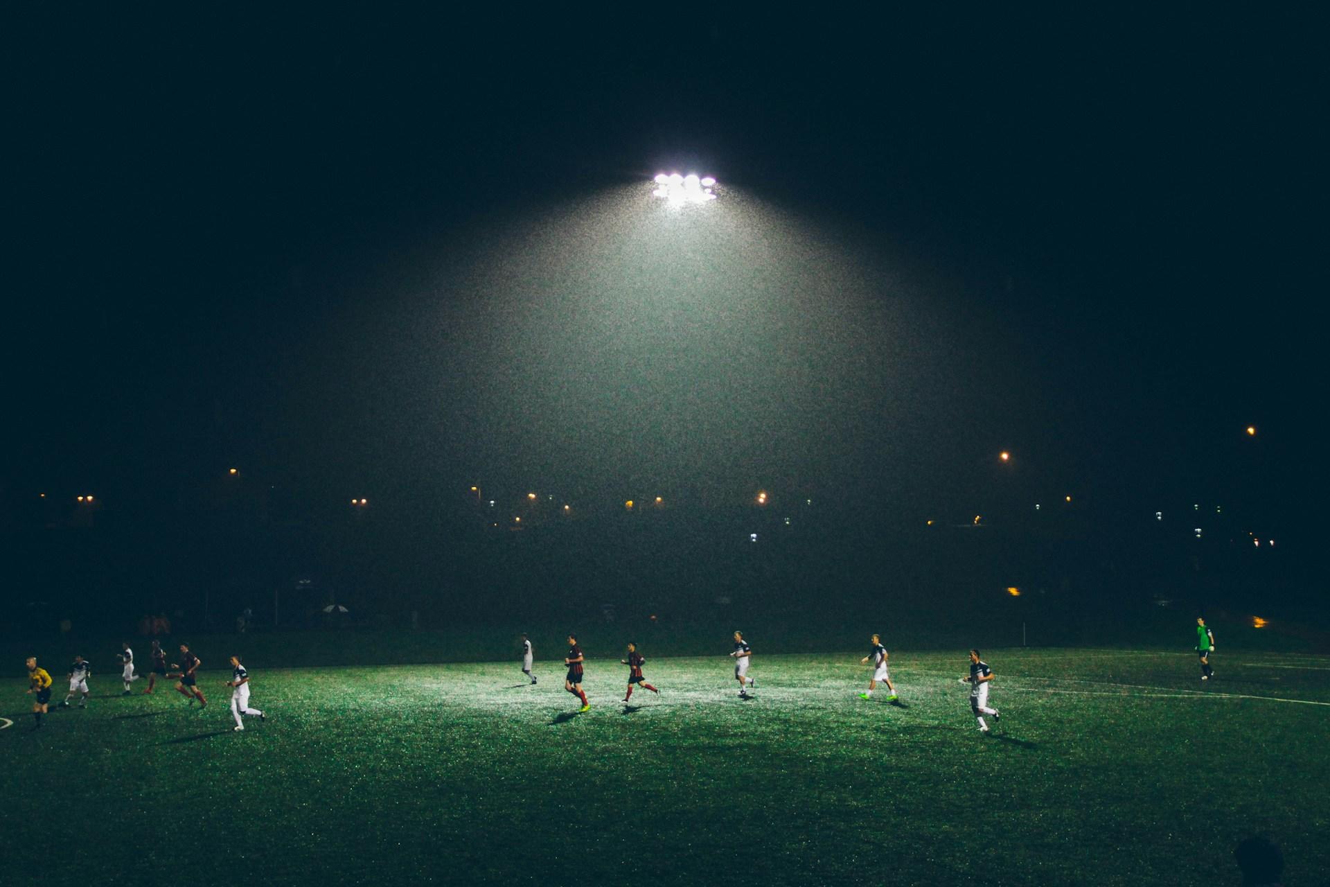 Fussballplatz mit Spielern im Regen.