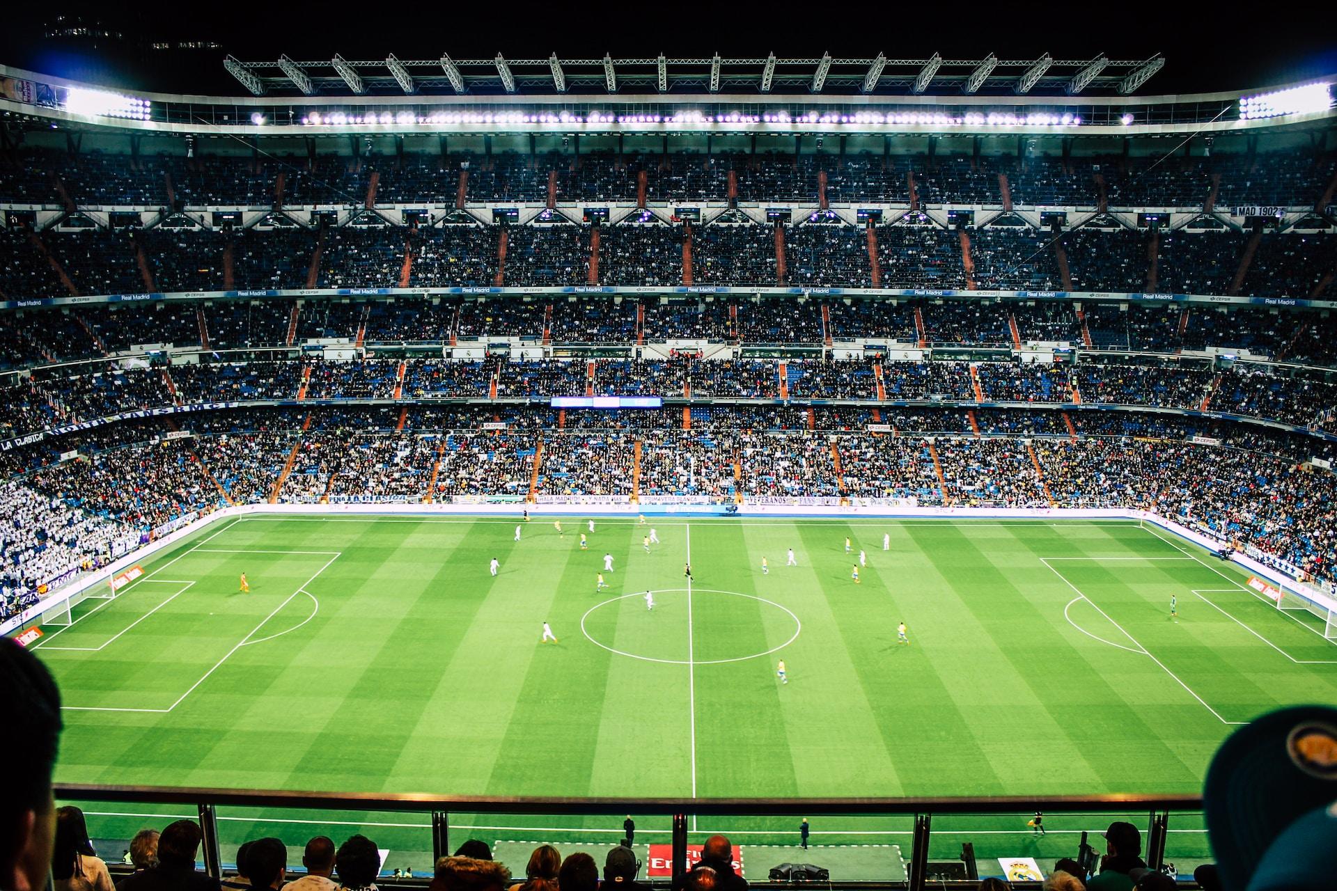 Fussballstadion voller Fans mit grünem Rasen.