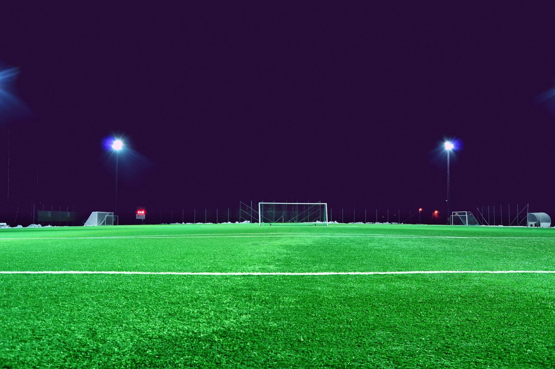 Fussballplatz mit Toren im Flutlicht.
