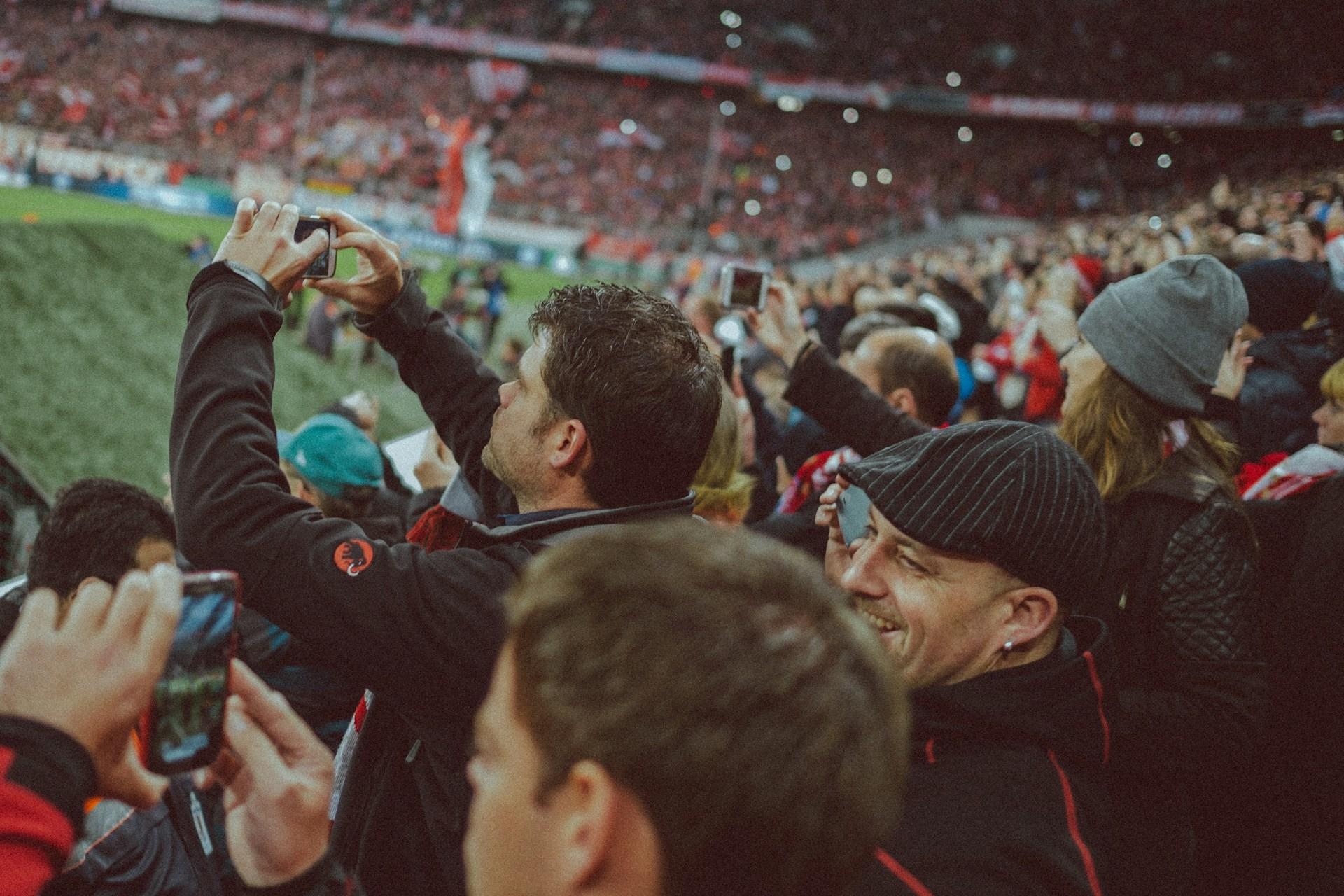 Fans mit Handy im Stadion.