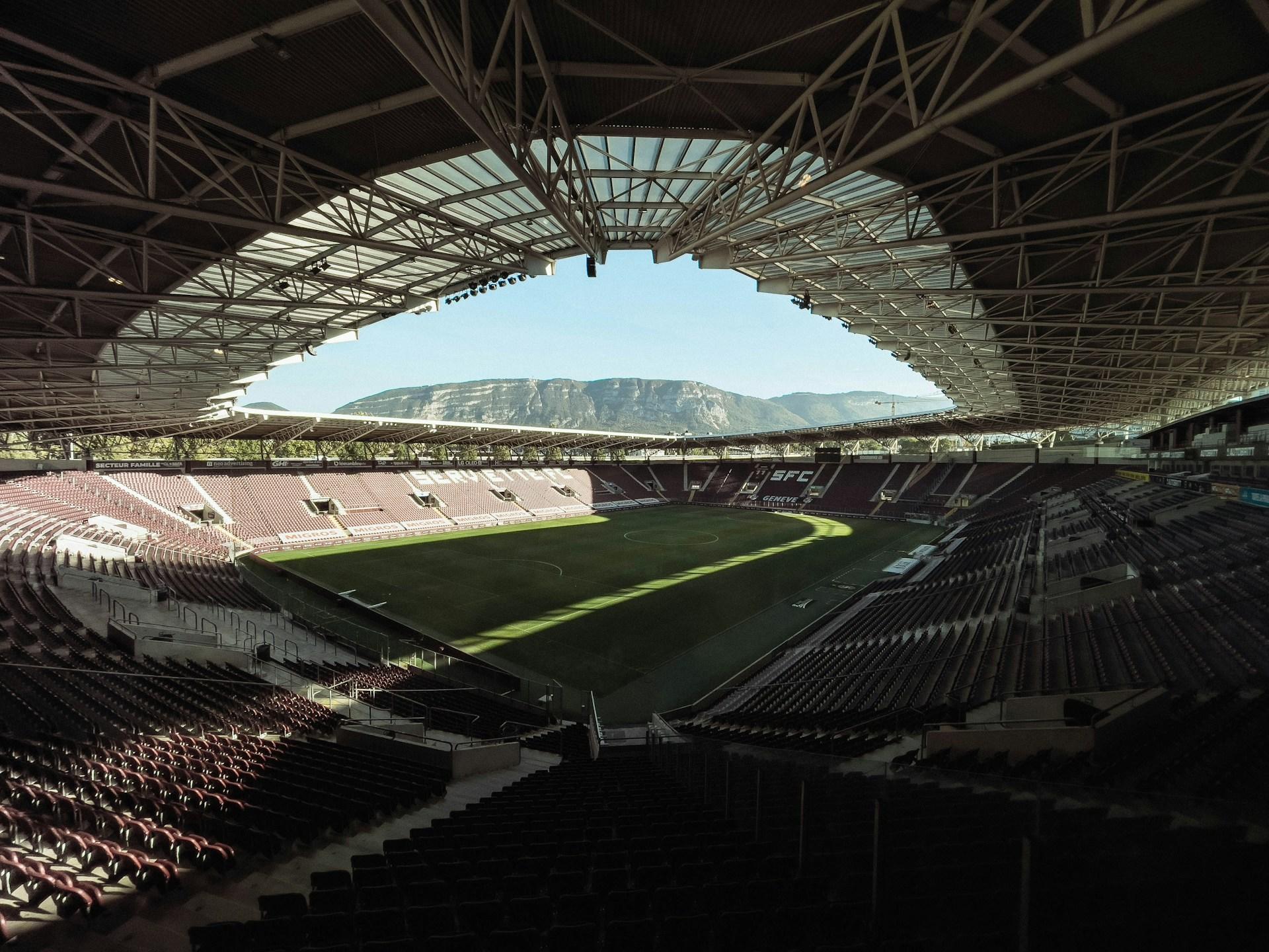 Fussballstadion mit leeren Plätzen und Blick auf Berg.