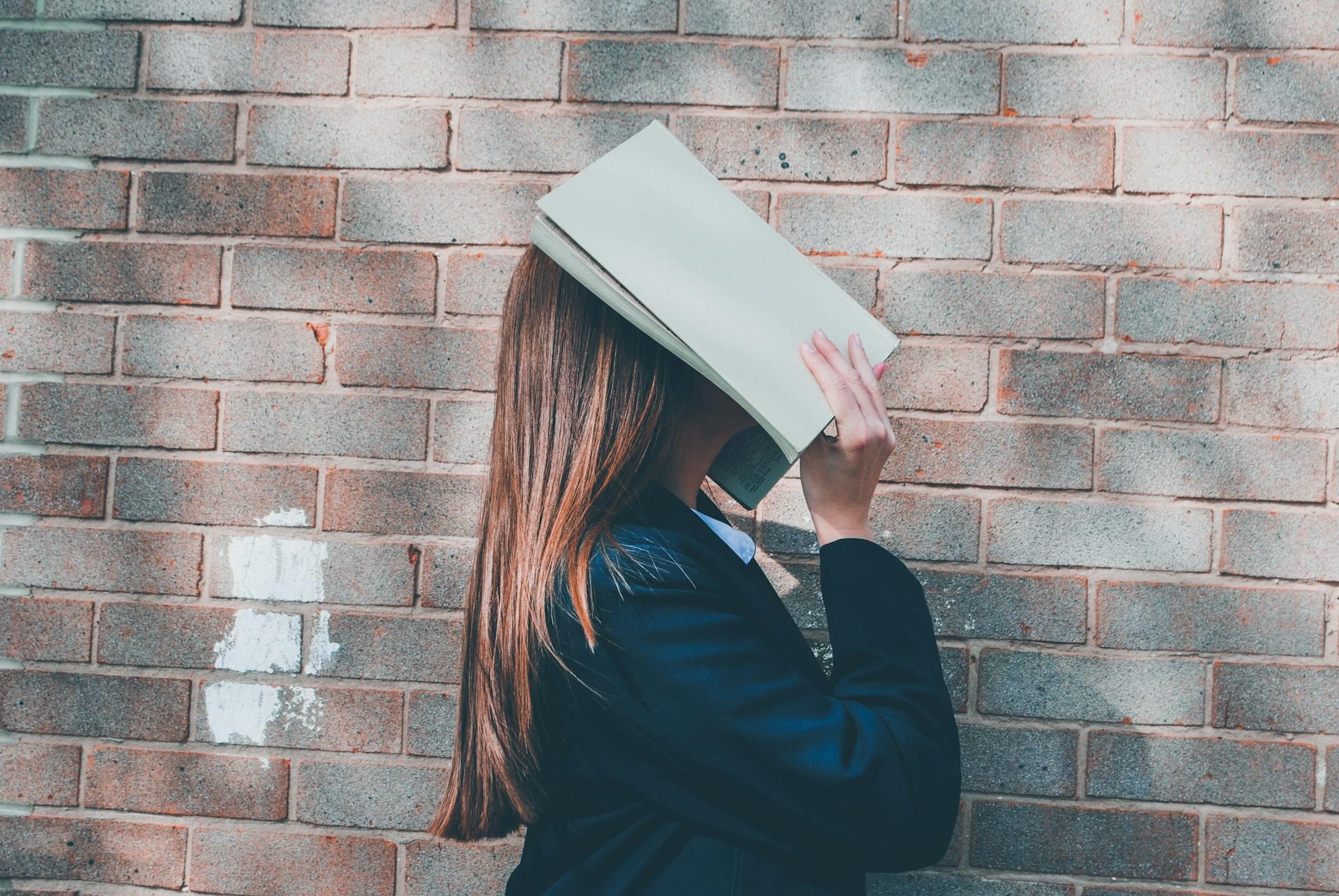 Frau mit Buch ueber dem Kopf