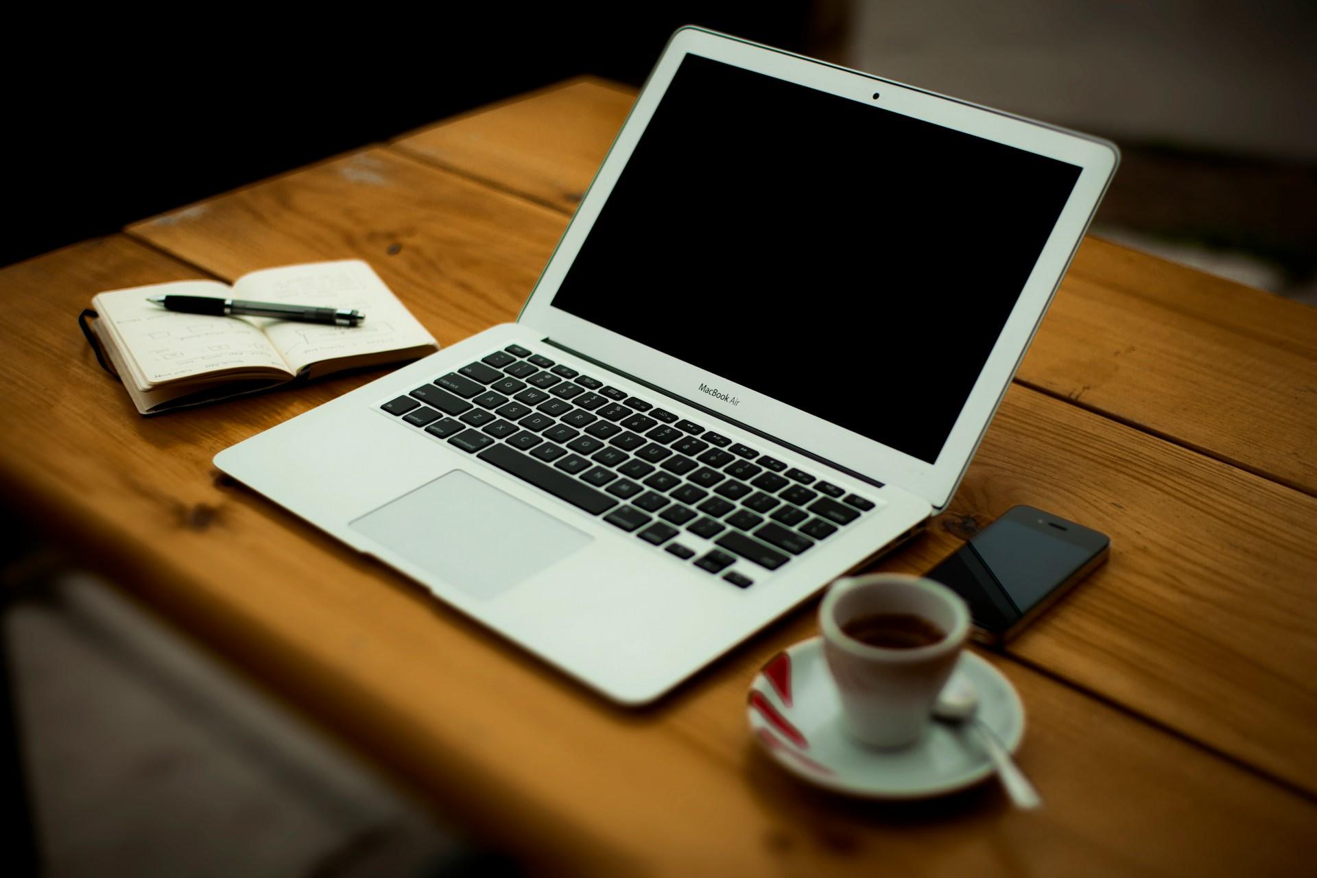 Ein Laptop und ein Notizblock liegen auf einem Tisch
