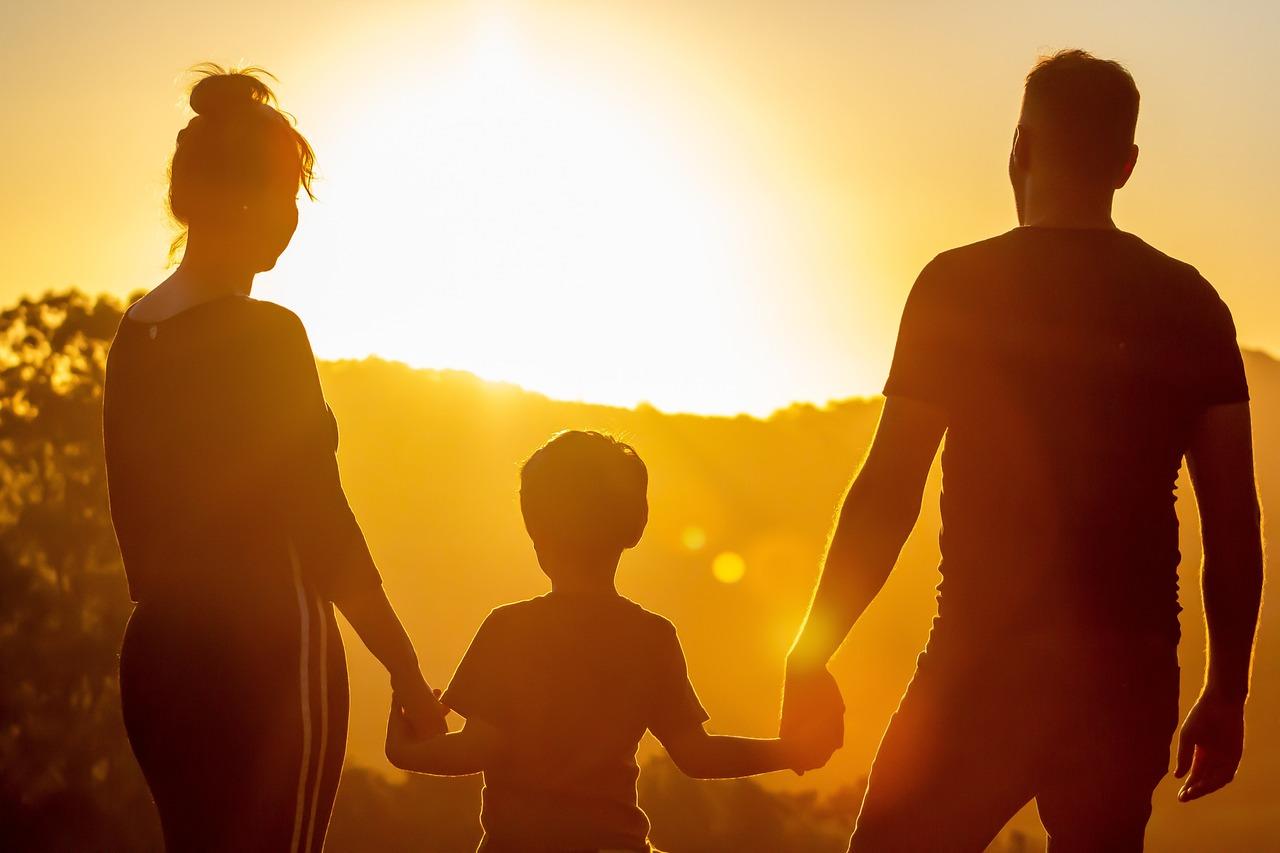 Eine dreiköpfige Familie schaut ins Abendrot