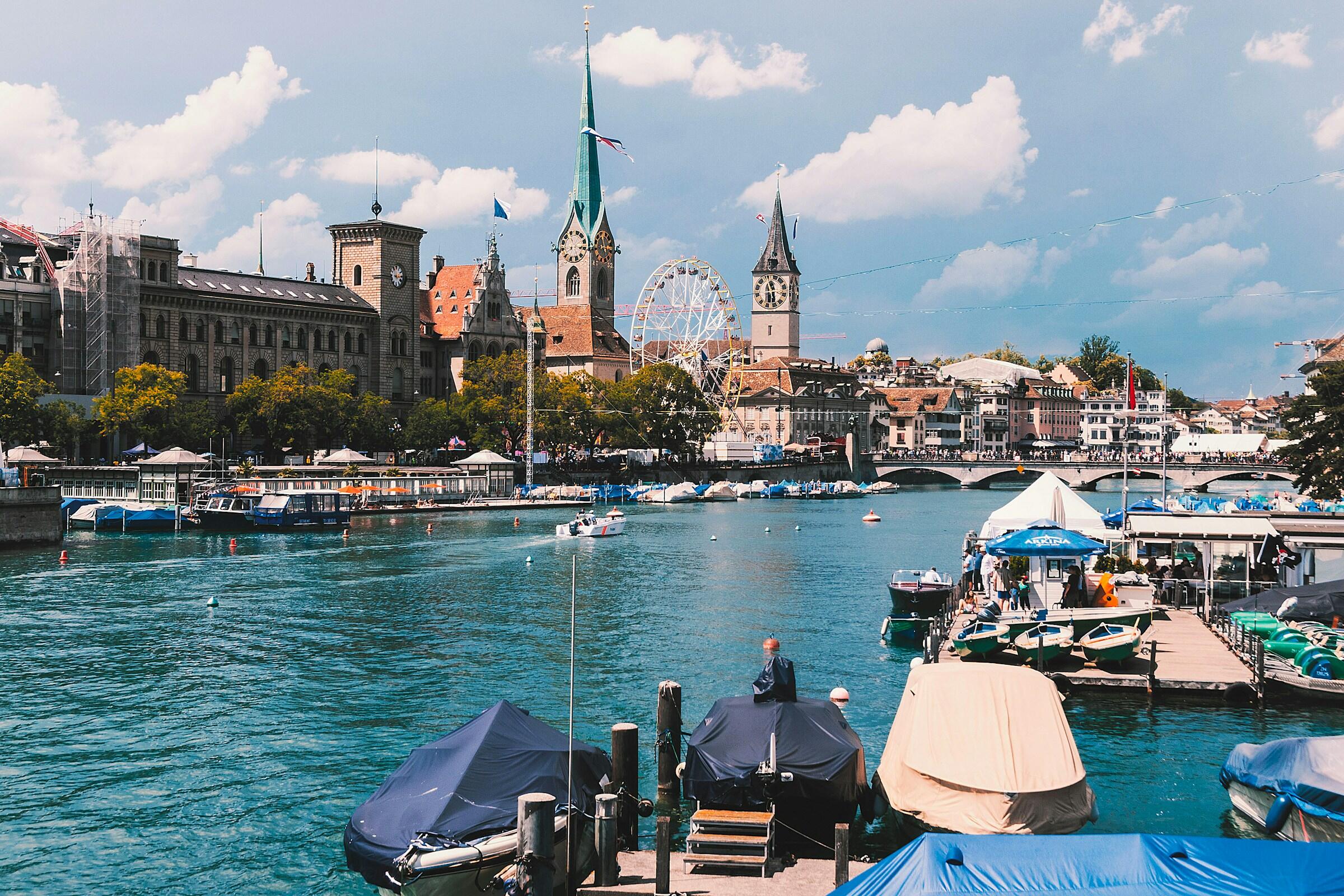EIn Gewässer in Zürich mit Booten und Gebäuden im Hintergrund.