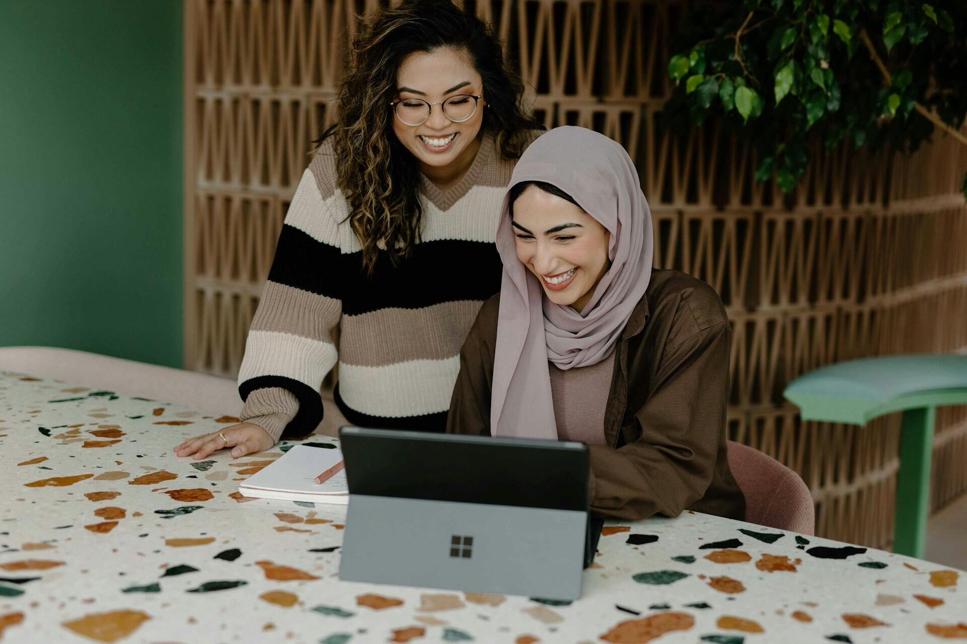 Zwei junge Frauen sitzen gemeinsam vor ienem Laptop.