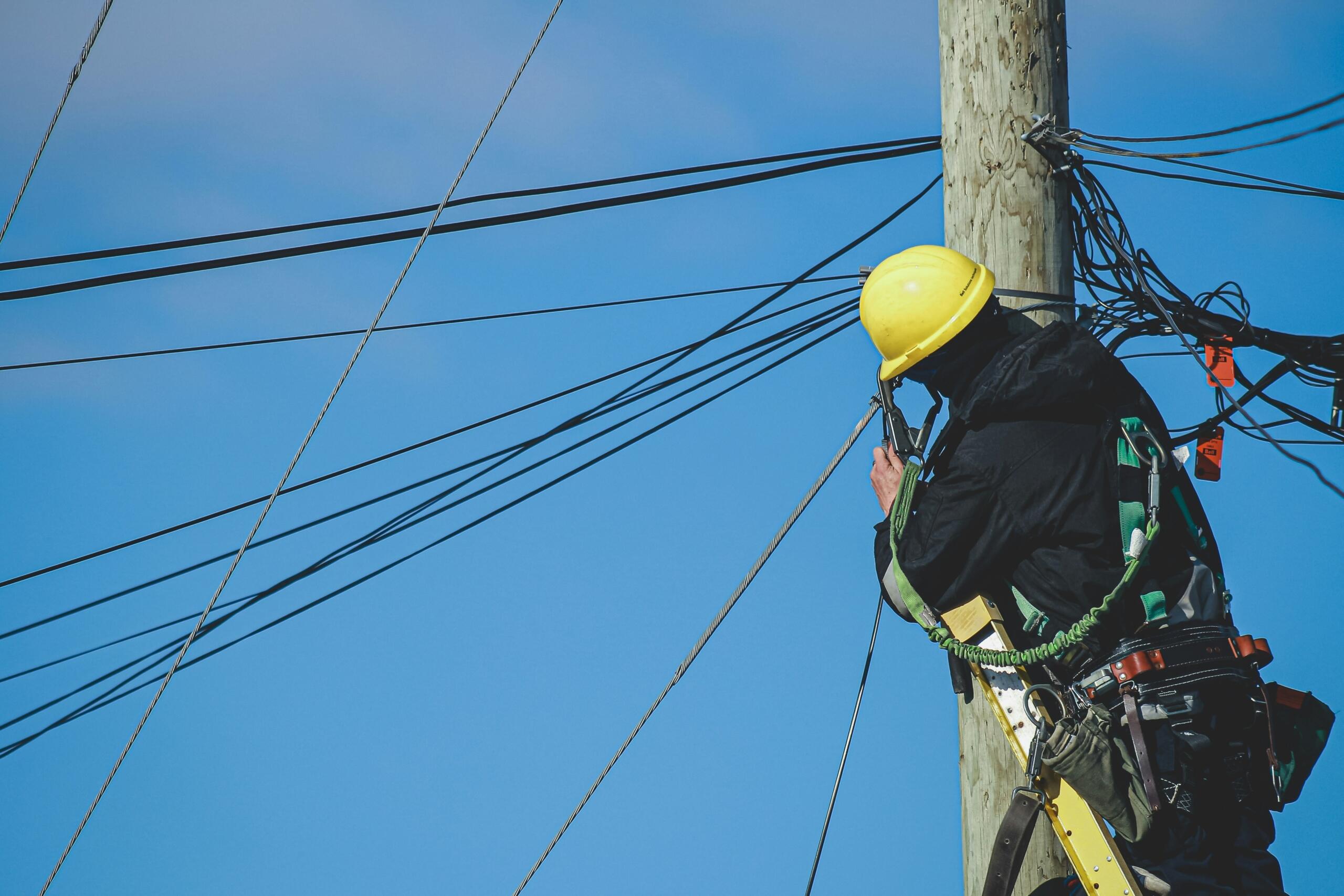 Elektrik töötab kaitsekiivri ja varustusega elektriposti otsas