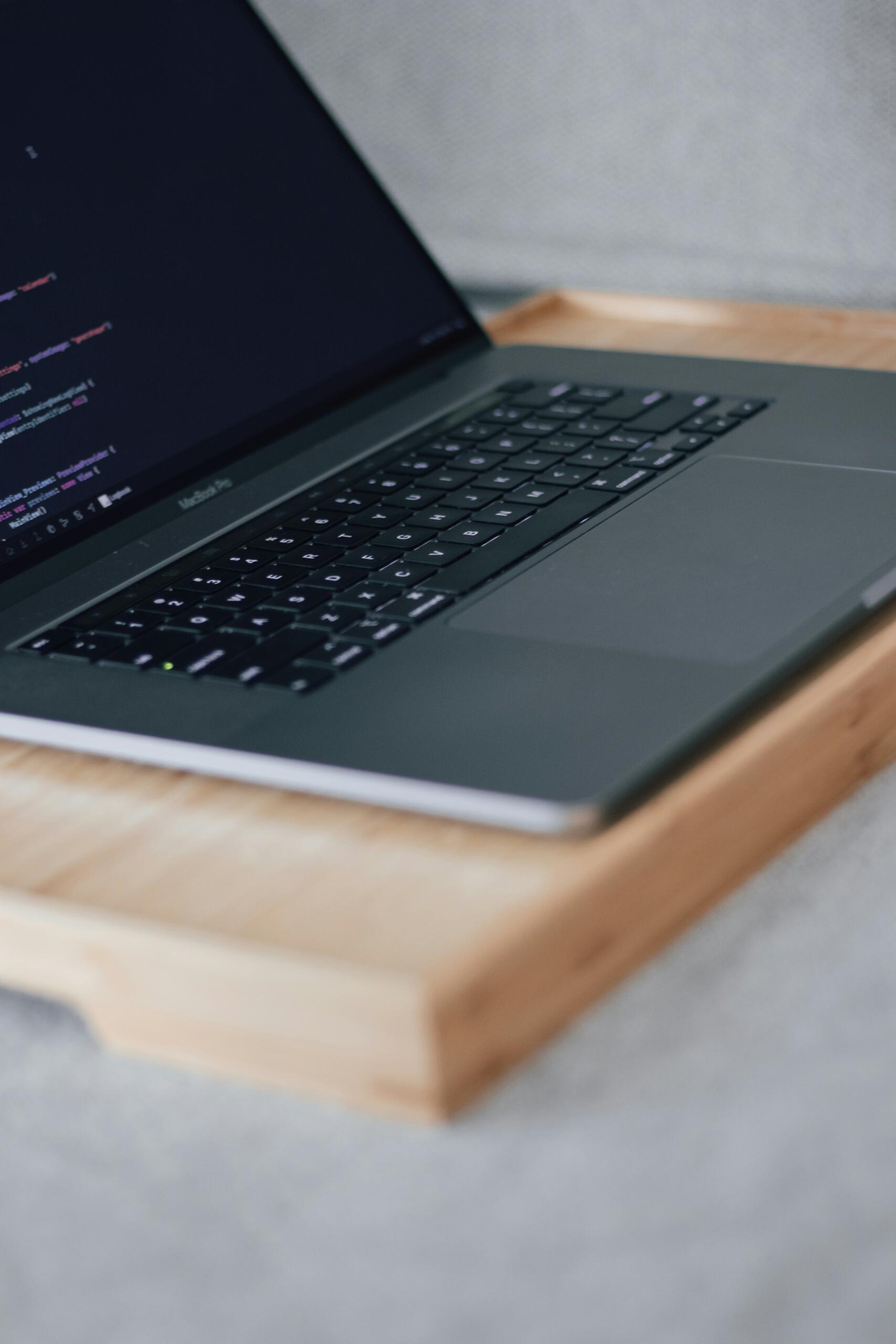 Lähikaader MacBook Pro klaviatuurist ja ekraanist, kus on Python-kood