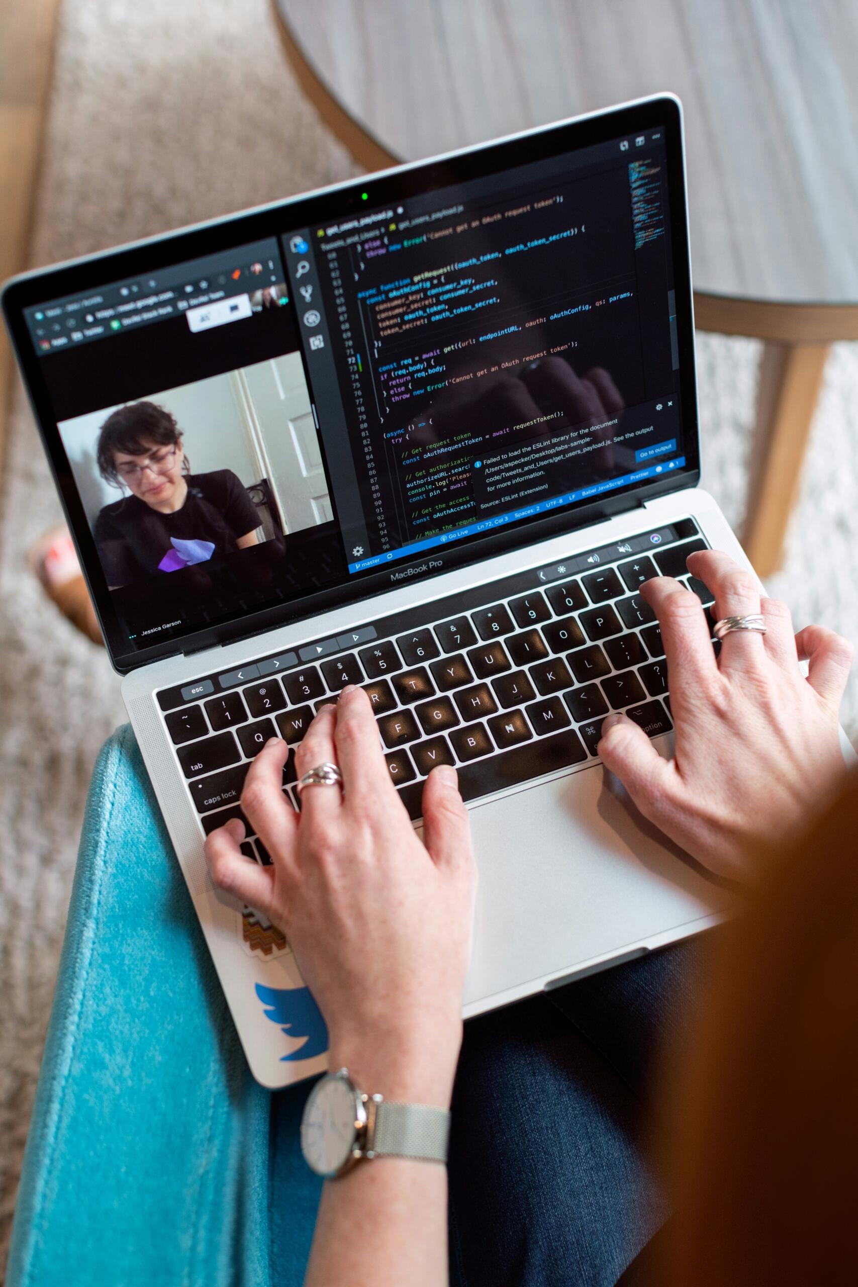 programmeerija arvutiekraanil on näha koodi ja videokõnet