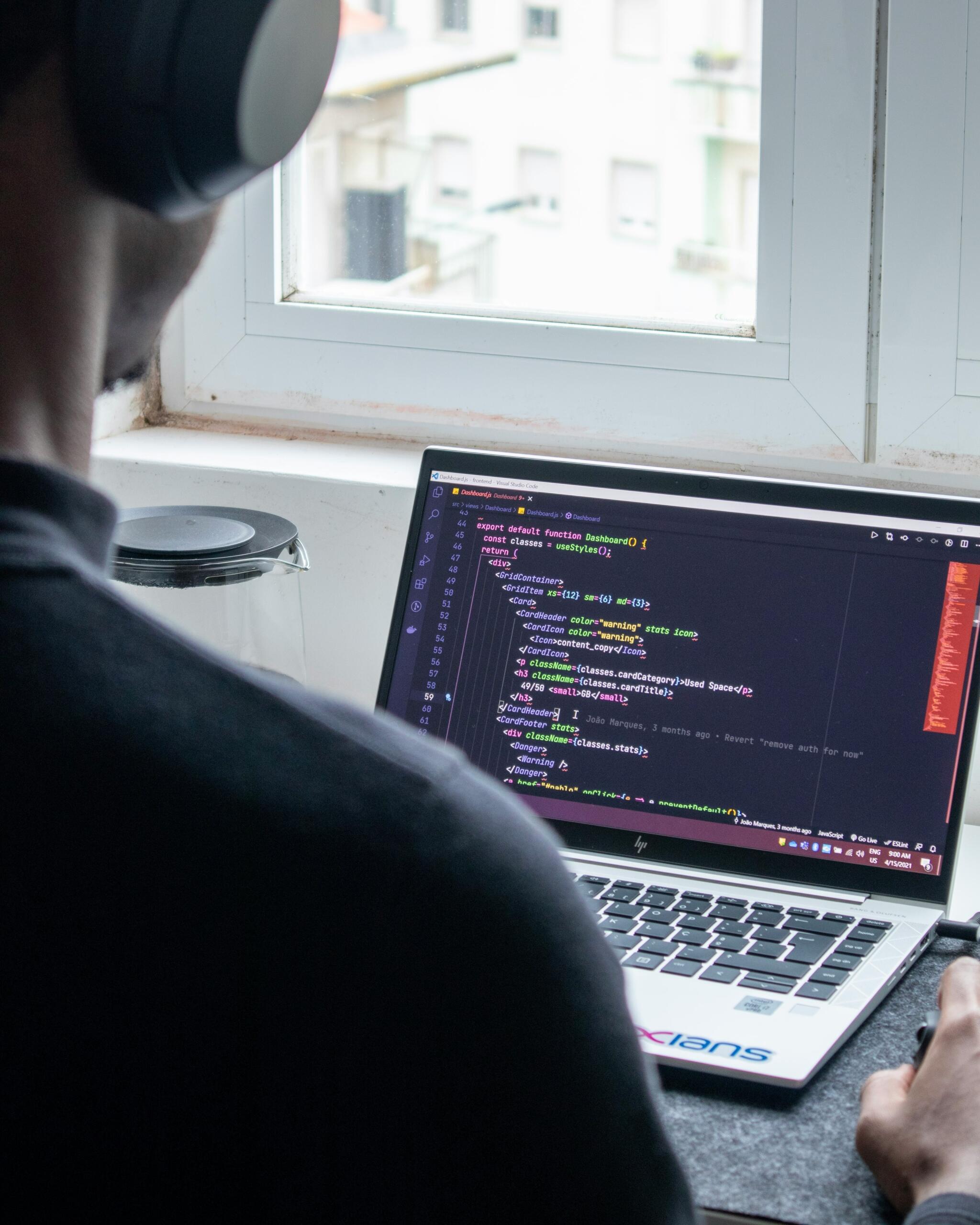 programmeerija sülearvutiga töötamas, fookuses ekraanil olev kood
